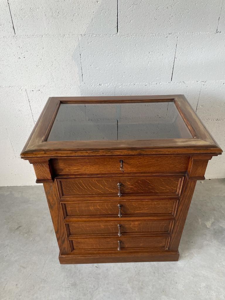 Magnificent piece of furniture known as collectors in solid oak. It has a display case in the upper part and opens on the front with 4 drawers.
This centerpiece piece of furniture is based on a plinth and has a secret closing mechanism.

Period: