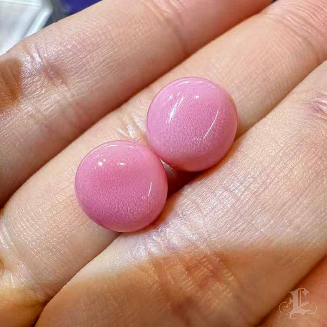 This matched pair of GUILD-certified conch pearls — 4.86ct and 6.51ct — radiates with the vivid glow of Flamingo Pink, their flame patterns softly dancing beneath the surface like whispers of sunlight through coral. Perfectly rounded and exquisitely