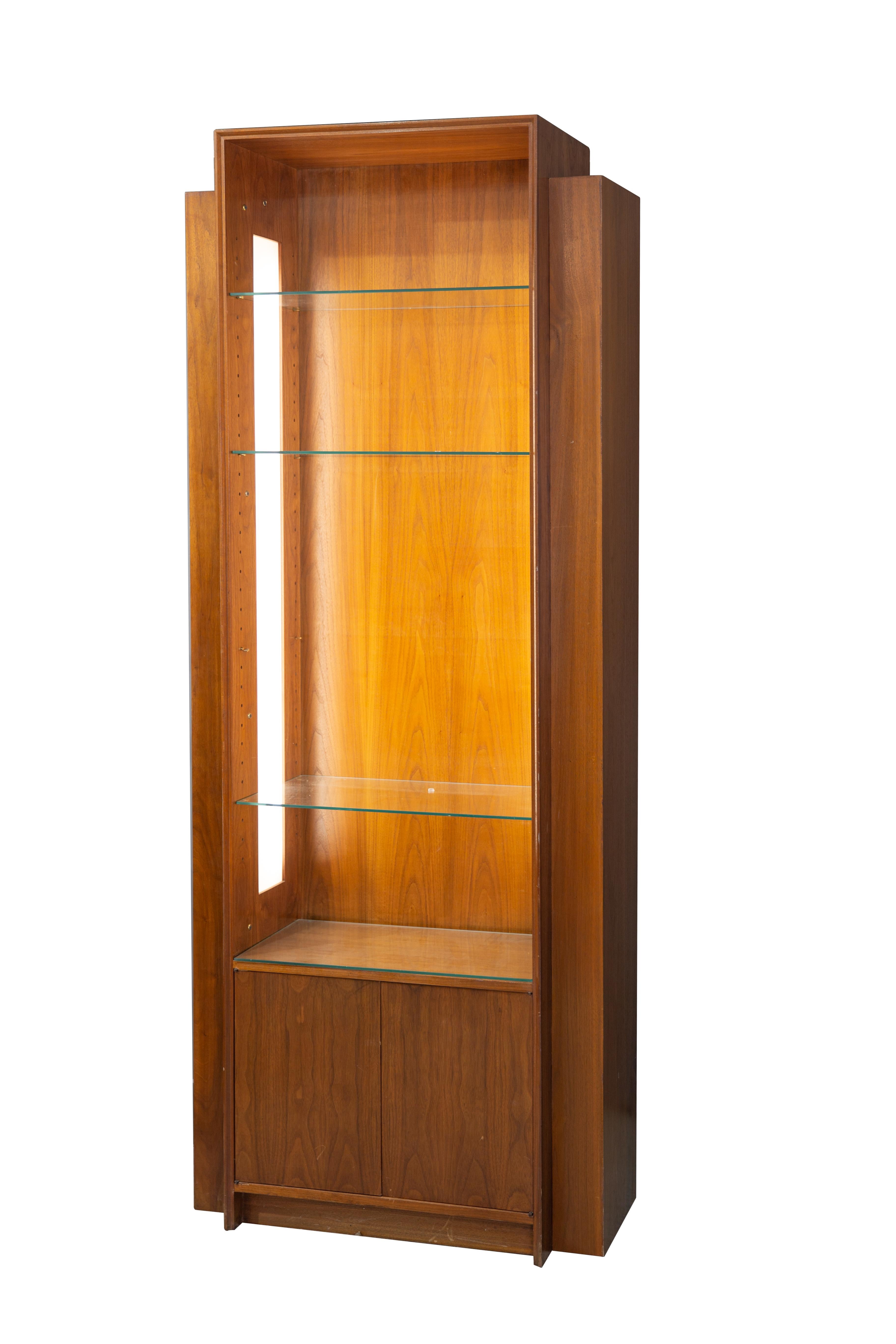 Mid-Century Art Deco skyscraper design open front walnut display cabinet with 4 glass shelves and interior side illumination. It’s in good condition and dates circa 1965. It measures approximate 84