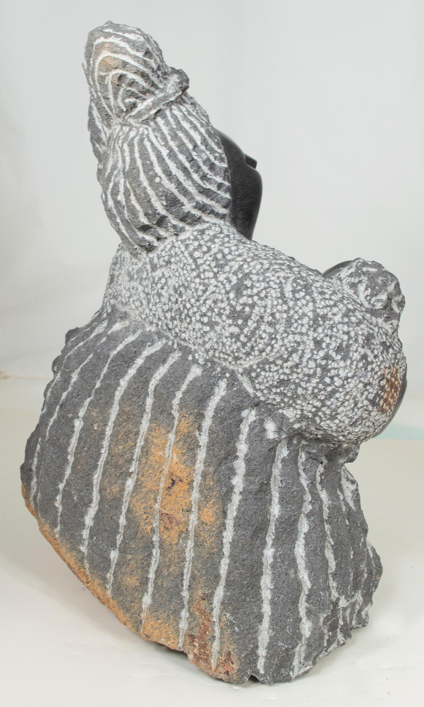 'Coming From Labor' is an original black serpentine sculpture by the celebrated second generation Shona artist Colleen Madamombe. The sculpture presents a character common to Madamombe's work: a woman with a round face and wearing a billowing,