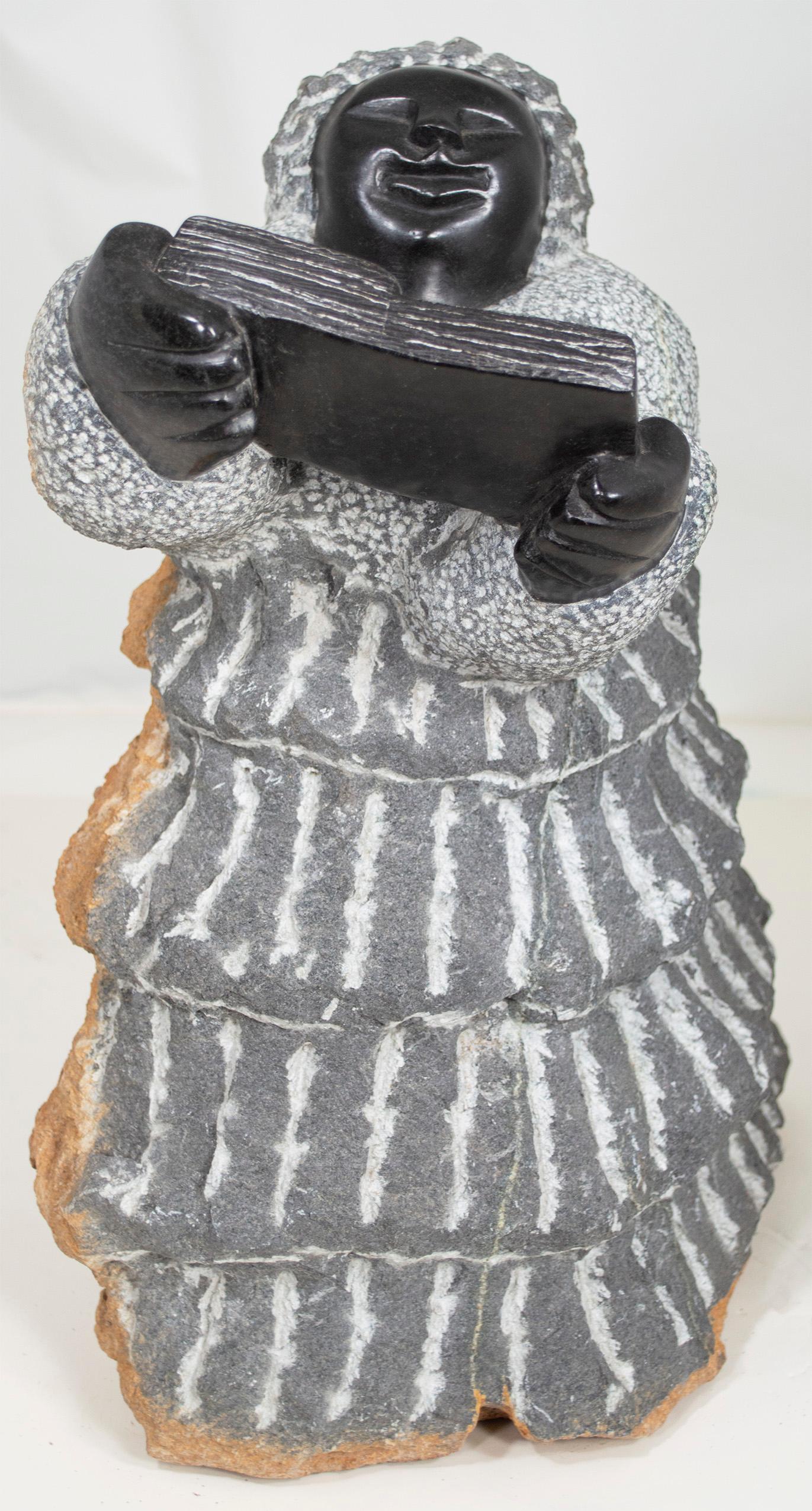'Teacher or Preacher' is an original black serpentine sculpture by the celebrated second generation Shona artist Colleen Madamombe. The sculpture presents a character common to Madamombe's work: a woman with a round face and wearing a billowing,