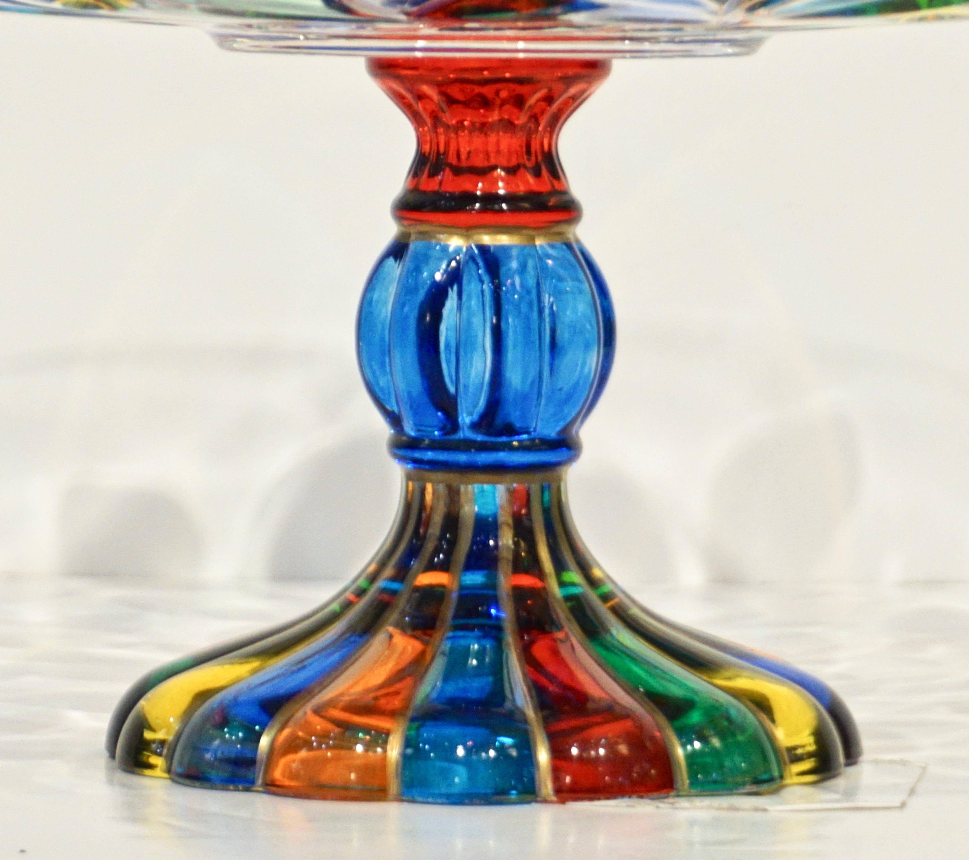 A brightly colored Venetian comport on pedestal, handcrafted in Italy by Vetrerie Colleoni, in crystal clear Murano glass happily overlaid on the exterior with an engraved pattern of leaves in green, yellow, turquoise, orange, red and blue colors.