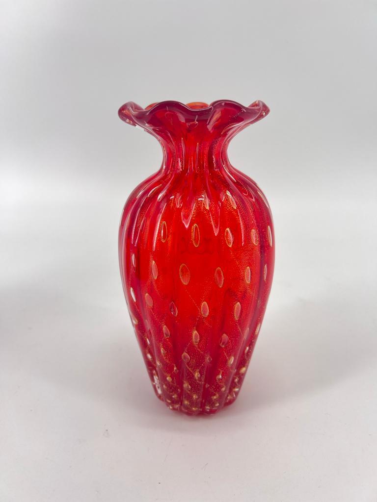 Presentiamo un magnifico set di 3 vasi d'arte, realizzati con pregiato vetro di Murano dal suggestivo tono rosso rubino. Ogni vaso vanta forme uniche e è finemente rifinito con luccicanti dettagli in foglia oro 24 carati e dettagli balloton