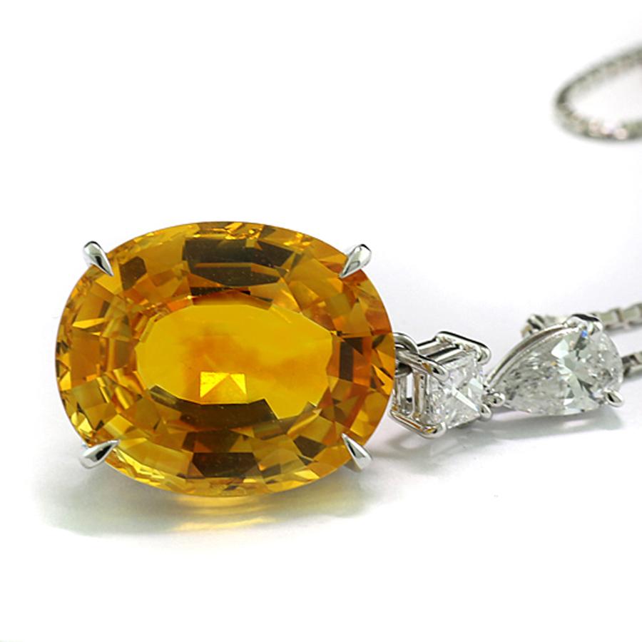 Pendant with one high quality sapphire from Ceylon, 12.34 carats, orange-yellow color and transparent quality, luminous brilliancy, oval cut, set in an oval bezel with four prongs, crowned by 2 natural diamonds in Princess Cut and Pear cut,