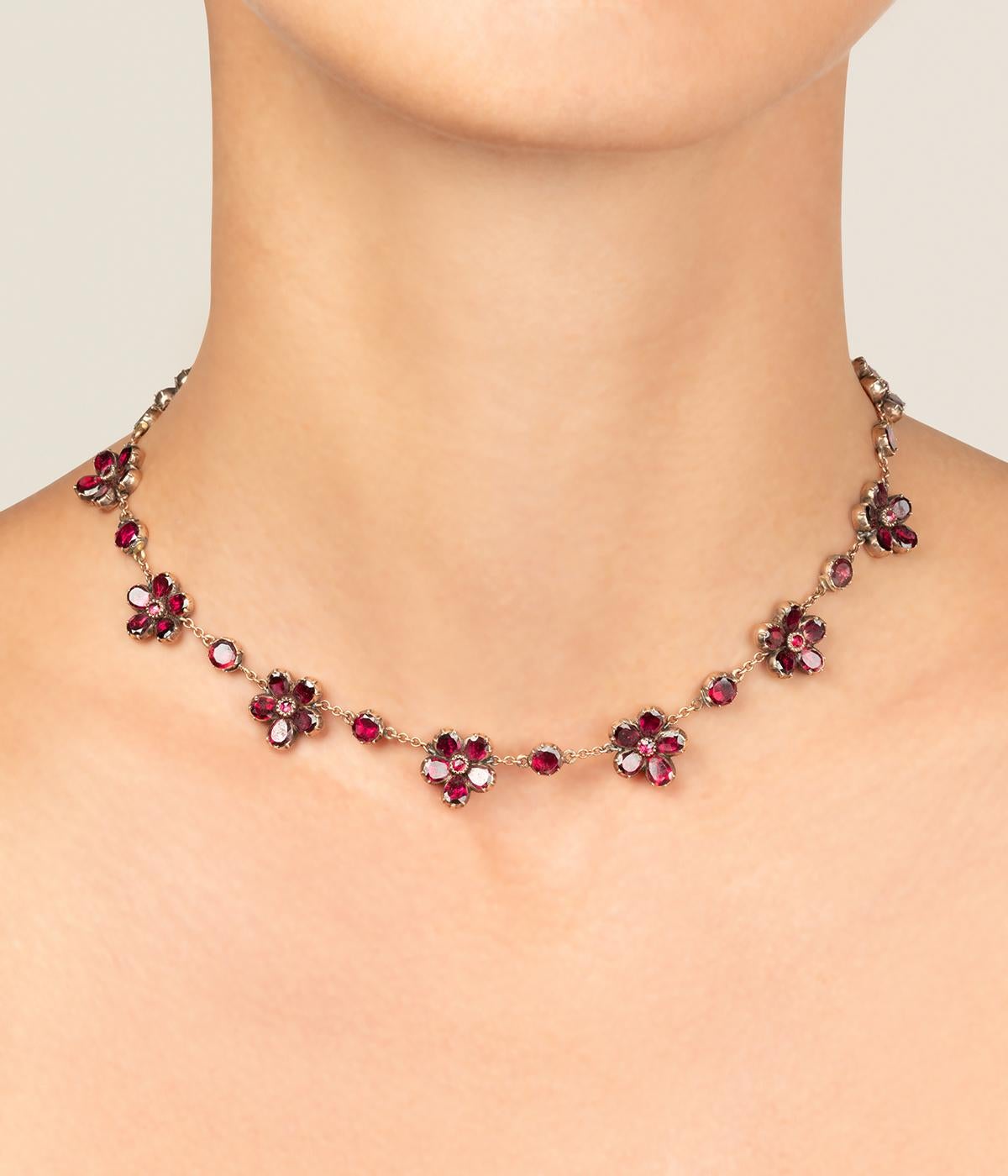 Collier antico in oro rosa 9 carati (350 millesimi) della fine del 19° secolo, ornato da 12 fiori di granata alternati da una pastello di granata, il tutto montato su paillon.

Poids total du bijou : 25,1 g environ.
Lunghezza 38 cm.
Diamètre fleur