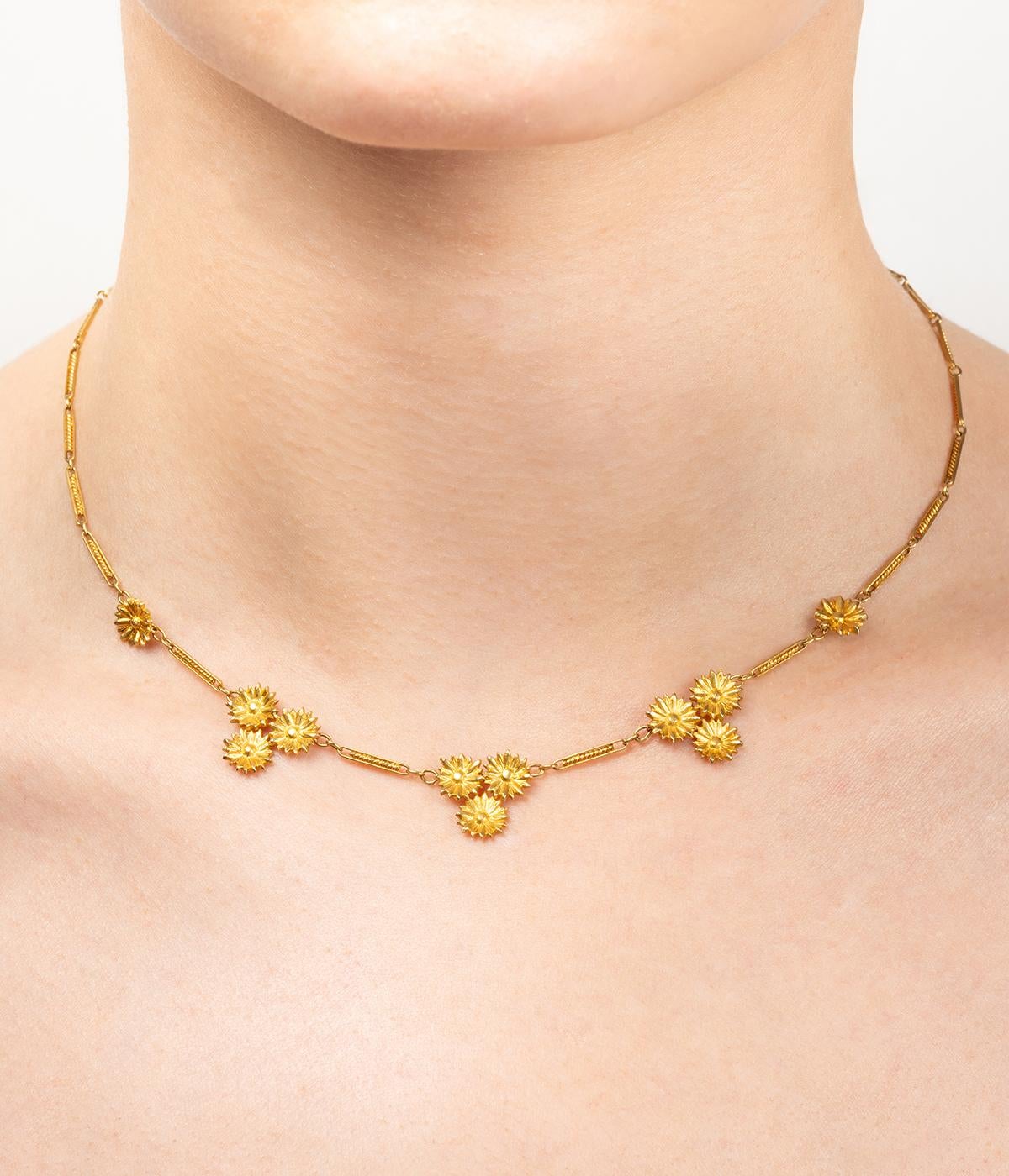 Collier drapperia Art nouveau in or 18 carati (750 millesimi), ornato da tre motivi formati da tre margherite, due motivi di margherite e una maglia fantaisie. 

Poids total du bijou : 9,1 g environ.
Lunghezza 41 cm.
Poinçon tête d'aigle.