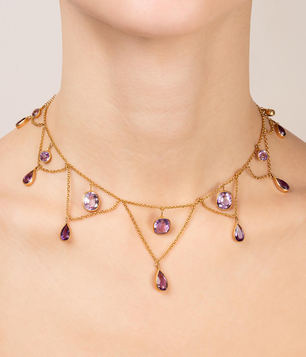 Collier draperie ancien en or 18 carats (750 millièmes) du début du 20ème siècle, orné de 7 améthystes en chute entre lesquelles 7 chaînes, également en chute, retiennent des améthystes taillées en goutte.

Poids total du bijou : 17 g