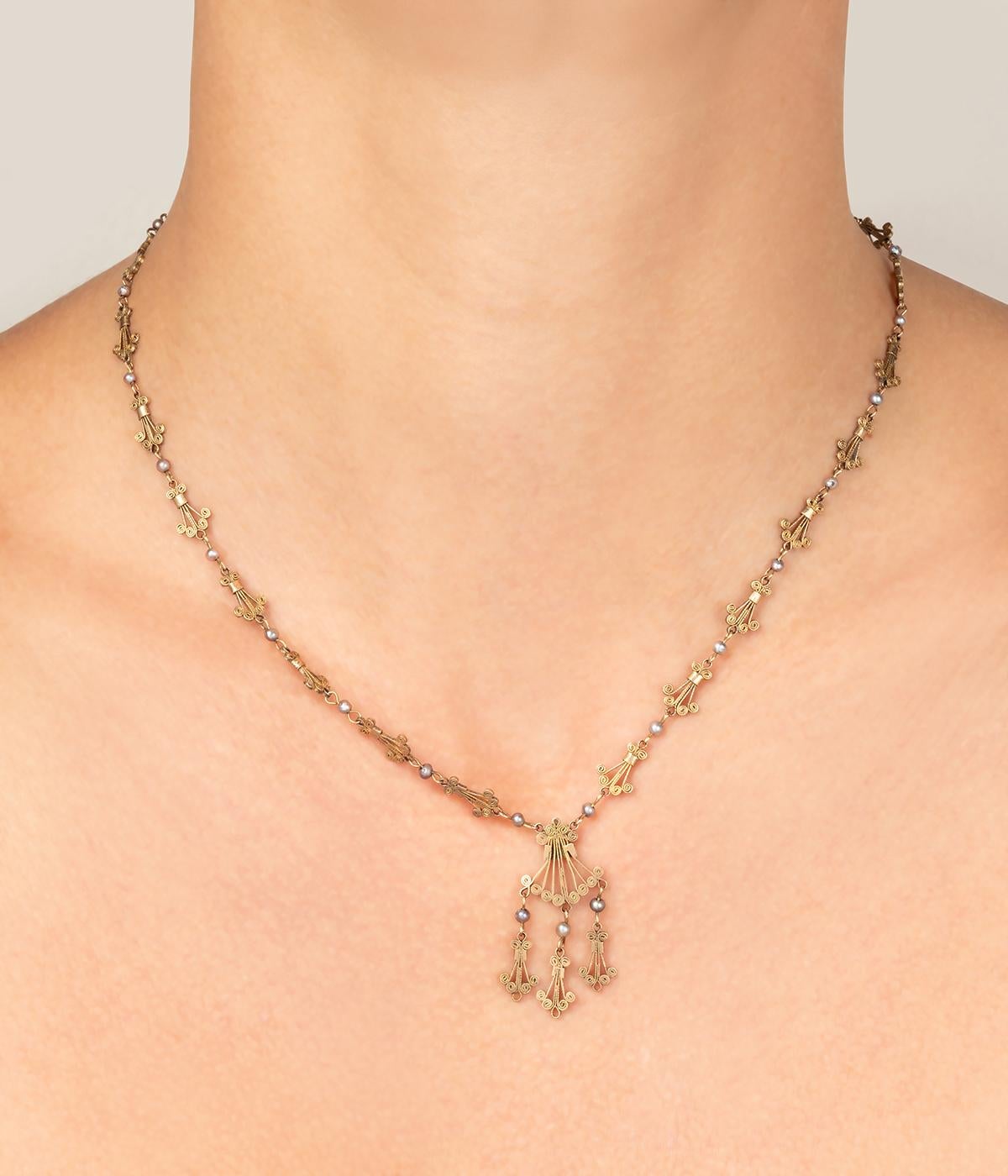 Collier antico in oro rosa da 9 carati (350 millesimi) della fine del 19° secolo, con montanti filigranati a forma di coda alternata di perle. Il motivo centrale, di forma diversa, è costituito da tre pampille.

Poids total du bijou : 7,67 g