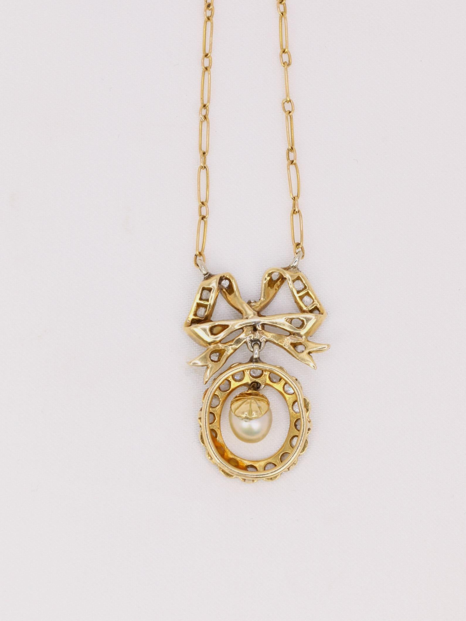 Collier en or 18k (750°/°°) composé d'un nœud Louis XVI surmontant un motif ovale diamanté soutenant une perle fine mobile. Les noeuds de style Louis XVI reviennent à la mode au moment de la période Belle Epoque et ce collier en est un joli exemple.