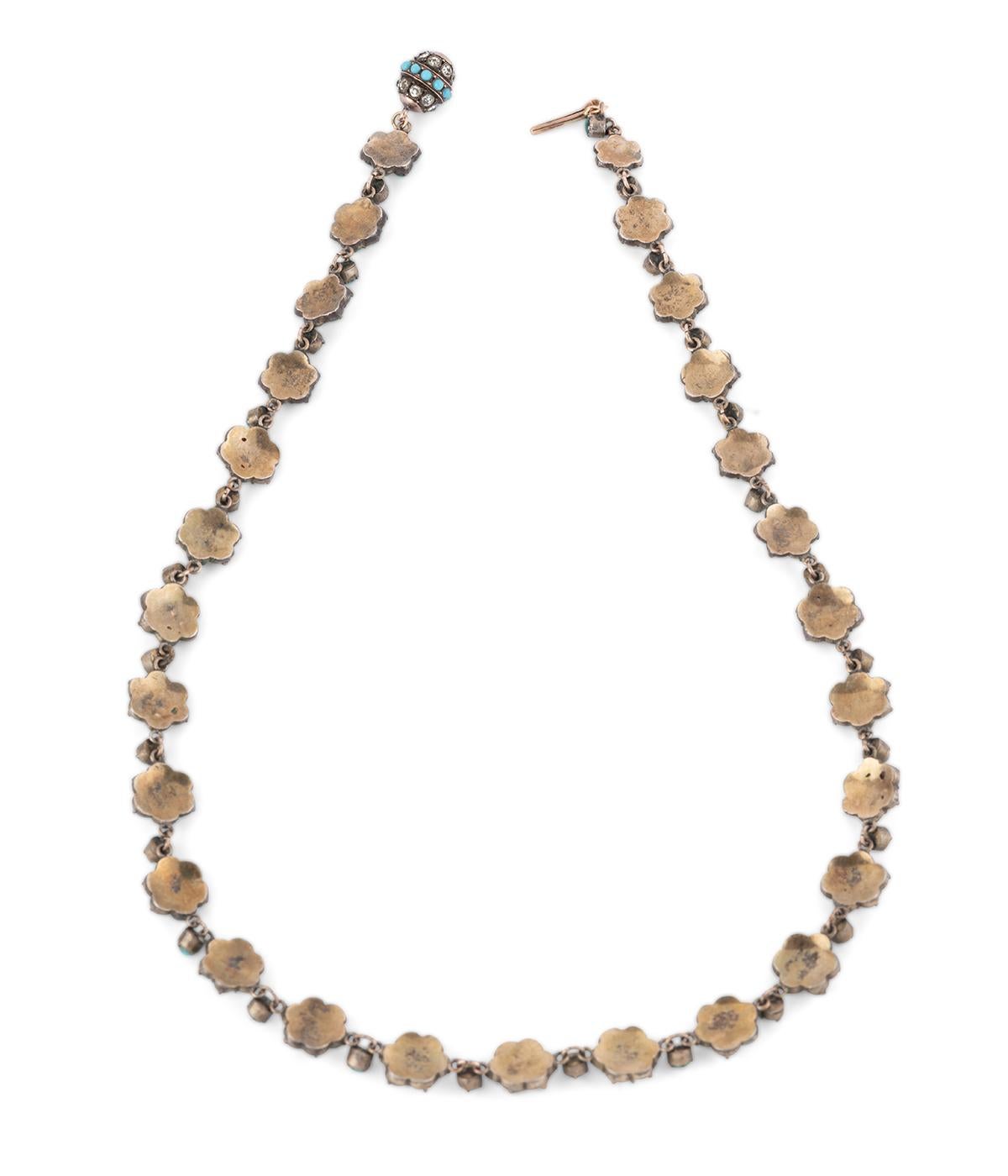 Collier rivière ancien en argent vermeillé du milieu du 19ème siècle, formé de 27 motifs de fleurs soulignés de cabochons de turquoise entre lesquels viennent s'intercaler un cabochon de turquoise. À noter le fermoir boule à cliquet souligné de deux