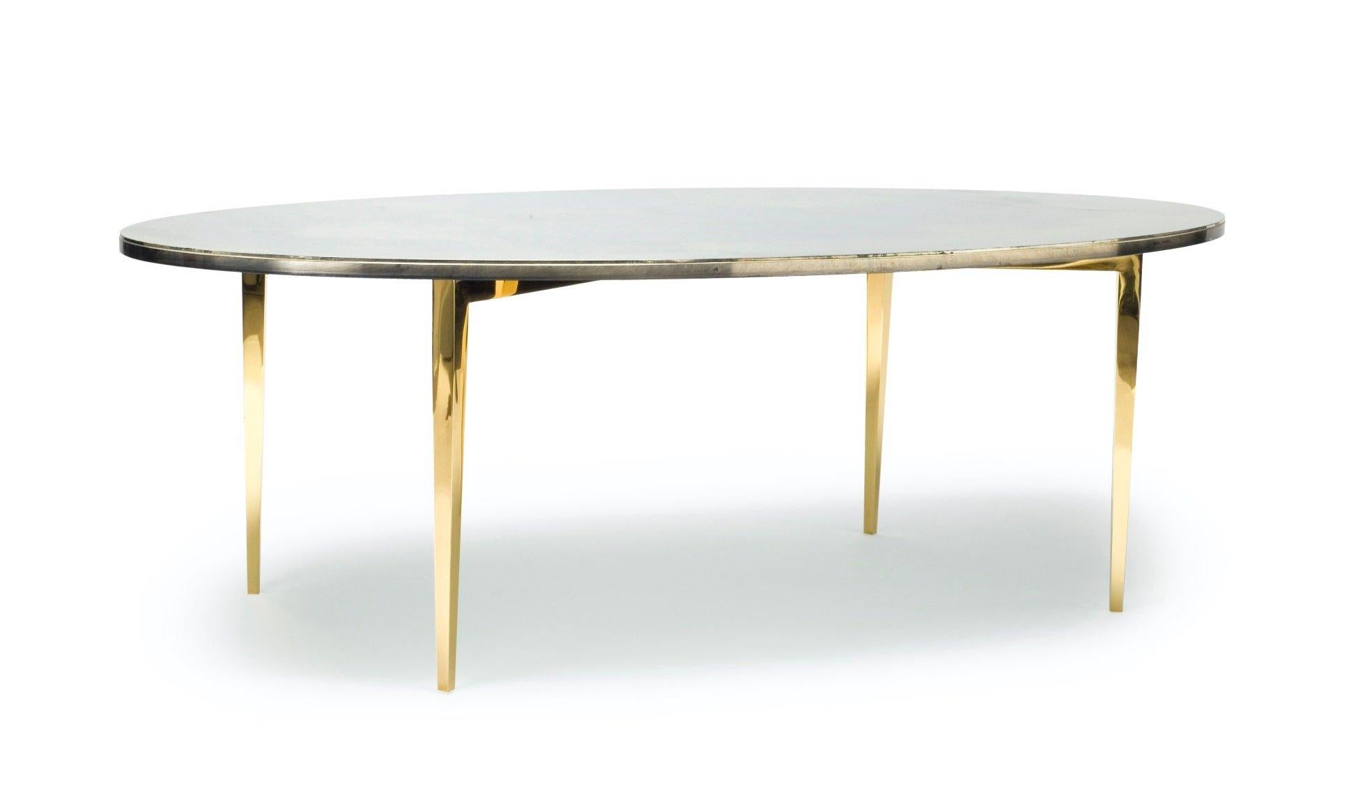 Oval glass cocktail table on brass base with hand-silvered glass top and protected with a glass coverslip.

Developed and created in England, the magical technique to create the bespoke finish on the glass is unique every time. No two pieces will