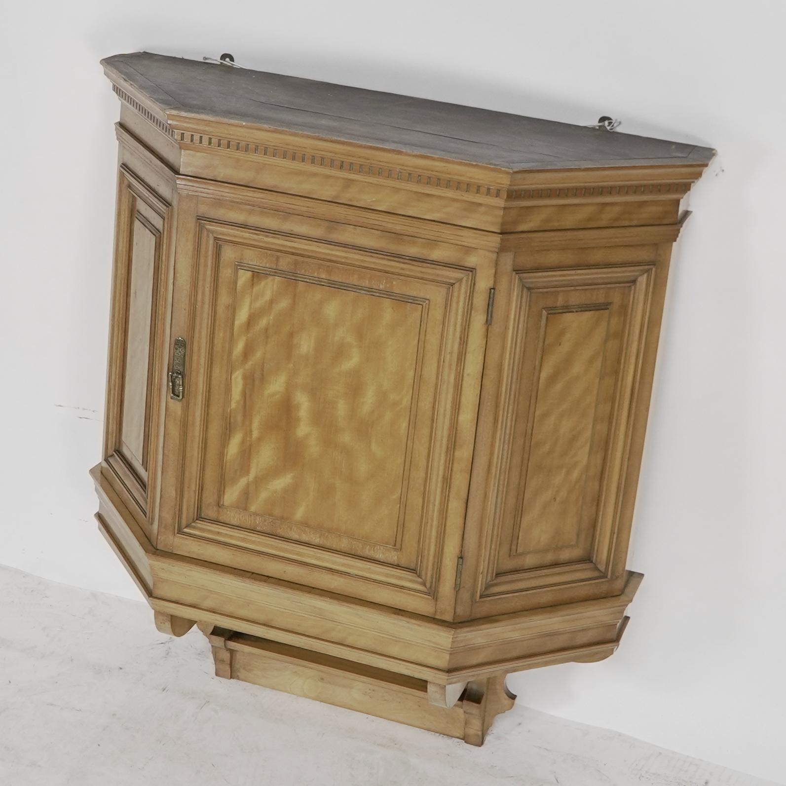 Collinson and Lock. An Aesthetic Movement Satin walnut breakfront wall cupboard with a dentil cornice, and Japanese basket weave detailing to the brass handle.
