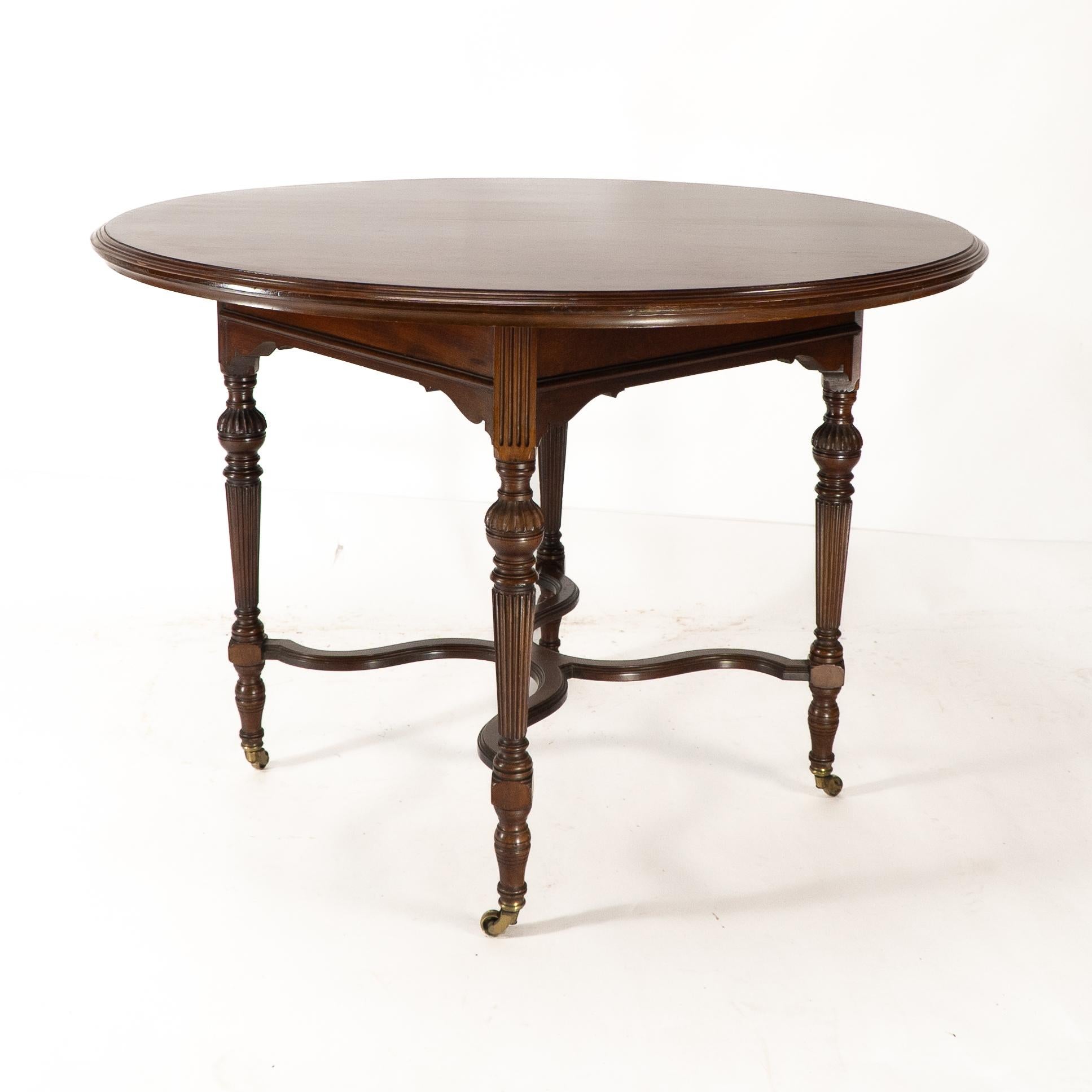 Collinson & Lock attributed. A fine quality Aesthetic Movement Walnut circular center table with a shaped apron & fluted legs united by serpentine stretchers.
