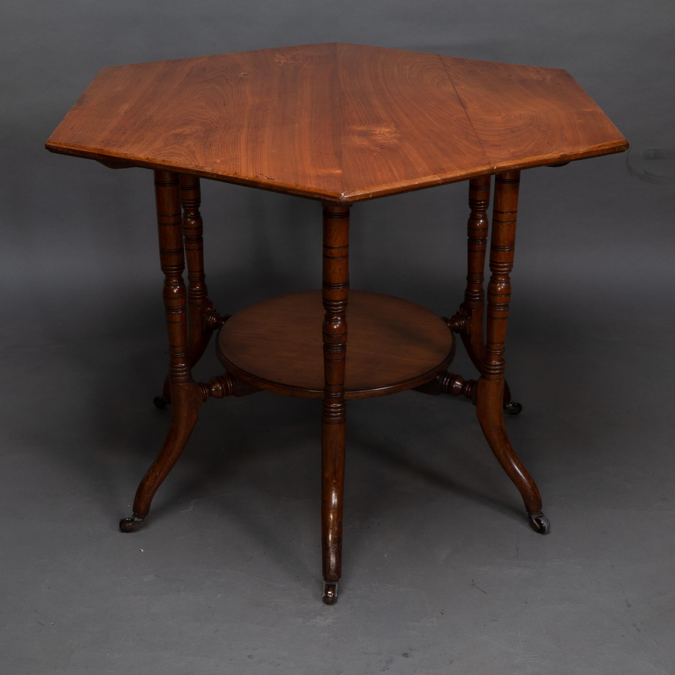 Collinson & Lock attributed. An Aesthetic Movement walnut six leg octagonal two tier center table with fine turned legs and out swept feet. The construction has radiating stretchers underneath the top which are joined to central disc with large