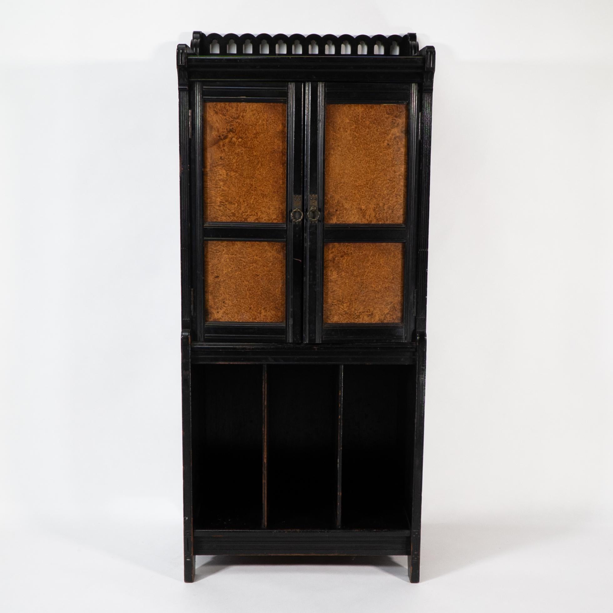 Collinson and Walton. A rare Aesthetic Movement ebonized music cabinet with pierced gallery to the top, wild burr walnut panels to the doors which open to reveal sheet music slides, with castellated brass backplates etched with fleur de lys and