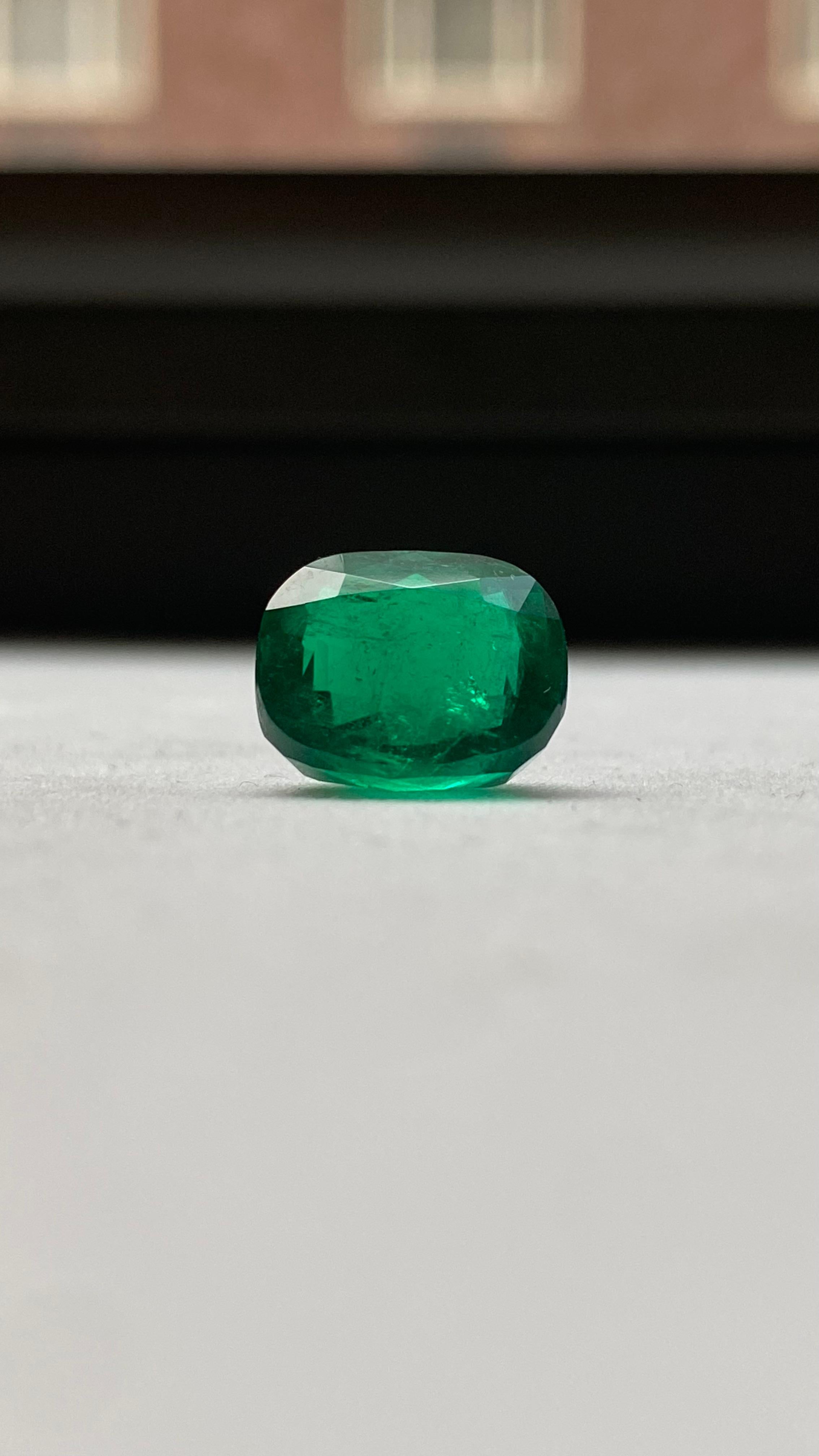 This exceptional loose gemstone is a Colombian emerald, weighing 7.26 carats, certified by the Gübelin Gem Lab. Cut in a classic cushion shape with a modified brilliant style, the emerald exhibits vivid green saturation, outstanding transparency,