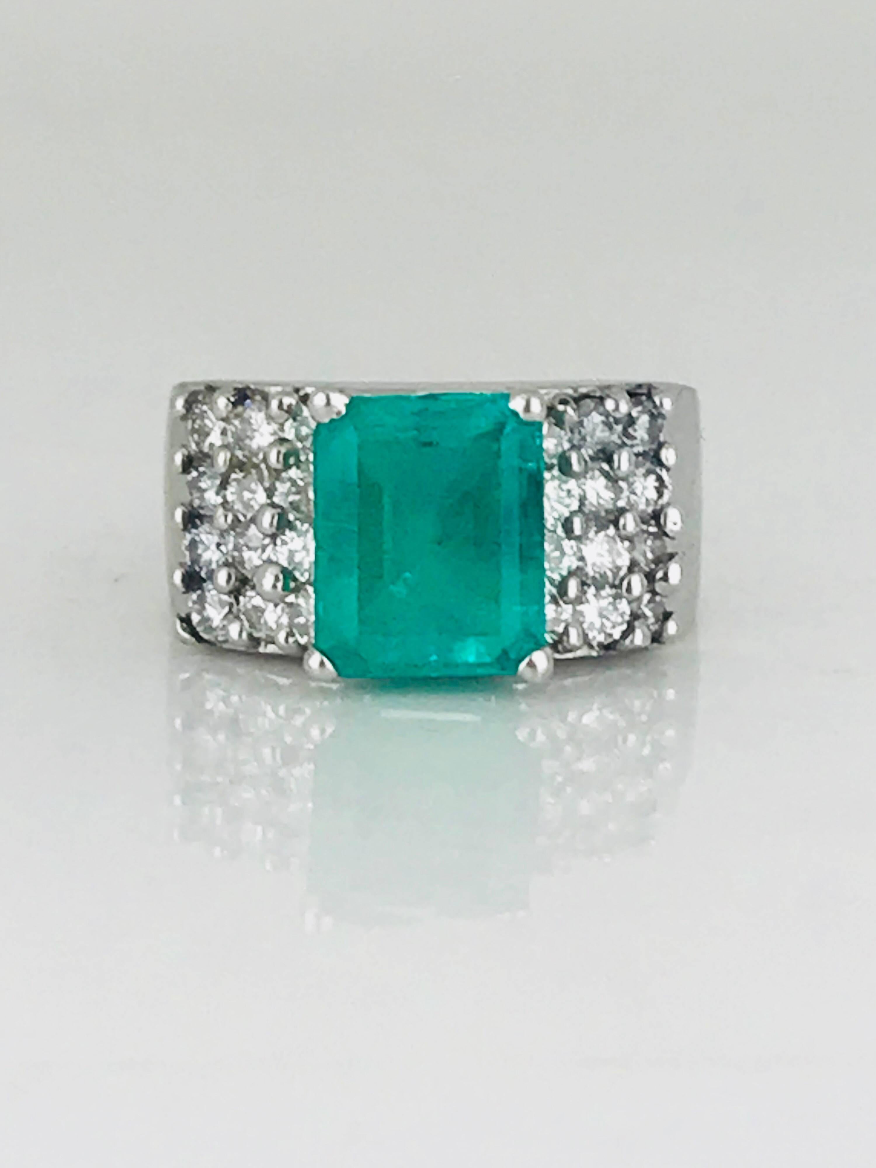 Contemporary, high polished, wide band, 18 karat white gold ring features a large prong-set emerald-cut Colombian emerald solitaire, accented with (24) shared-prong round brilliant diamonds.

Colombian emerald measures 10.24 mm x 8.32 mm and weighs