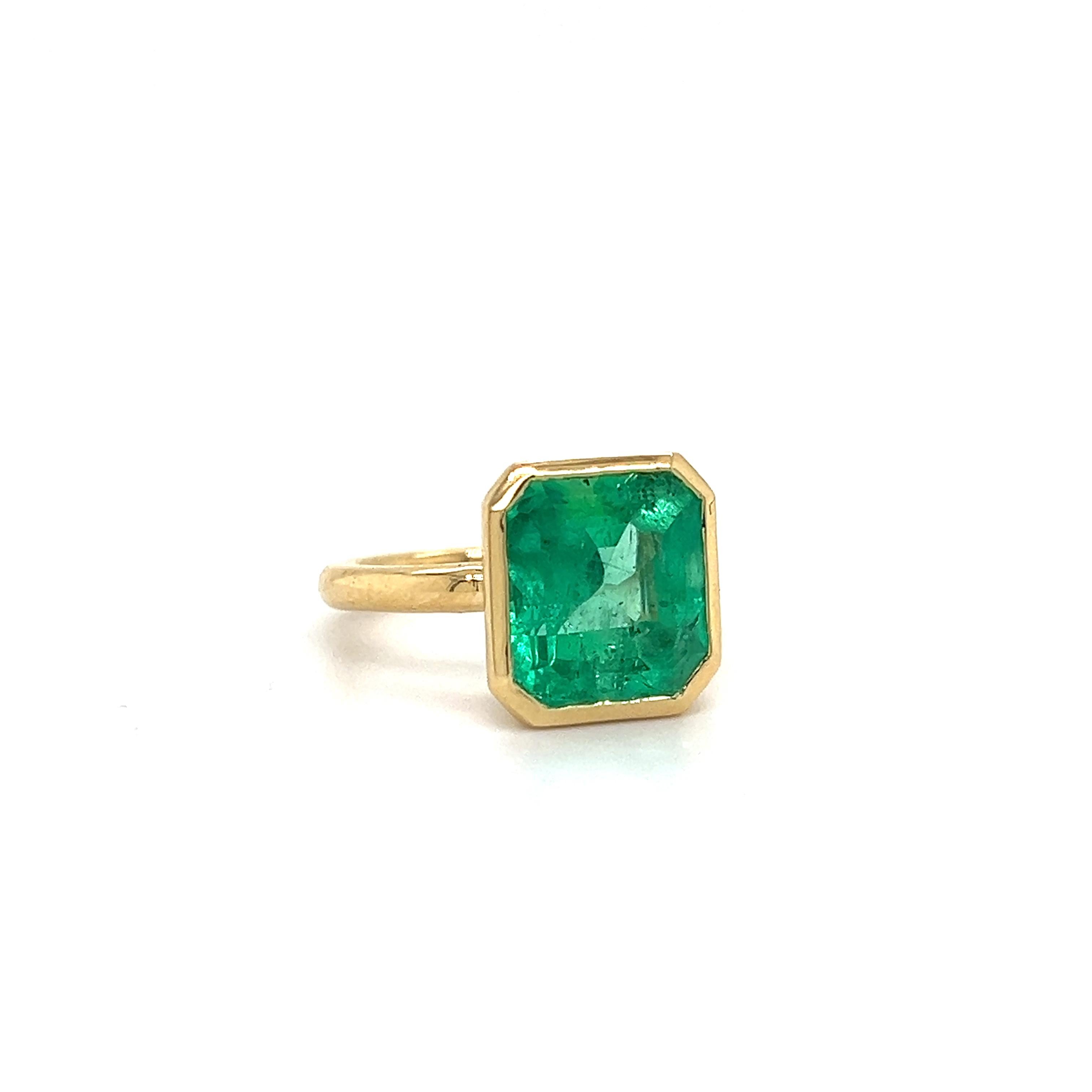Beautiful hand made ring crafted in 18k yellow gold. The ring highlights one Colombian emerald gemstone that displays an electric green color. 
The emerald gemstone weighs 6.10 carat and is bezel set in the 18k gold ring. Sharp edges make this