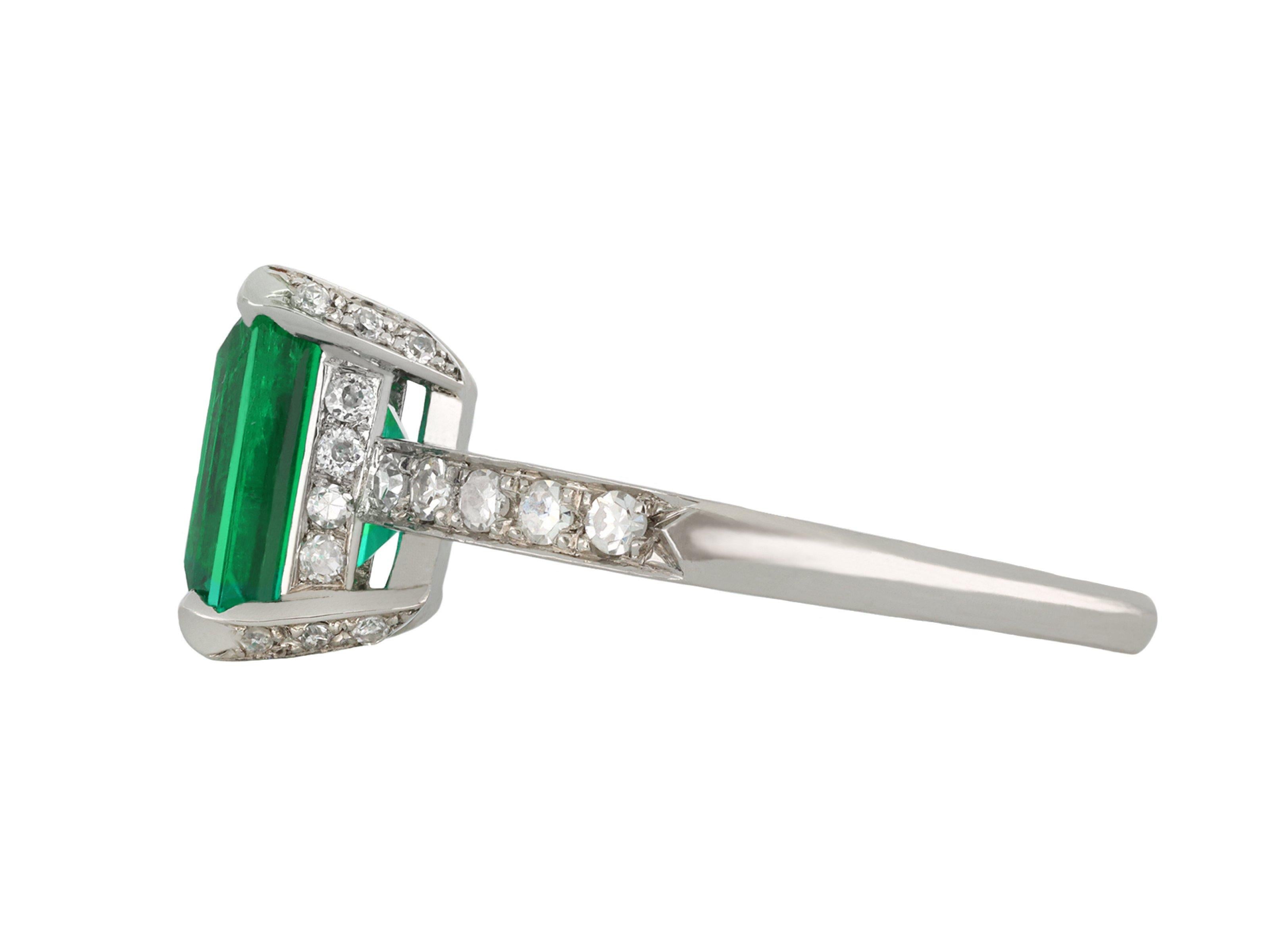 Colombian emerald and diamond flank solitaire ring. Set to centre with a rectangular emerald-cut natural Colombian emerald with minor oil, in an open back claw setting with a weight of 2.08 carats, further set with thirty six round eight-cut