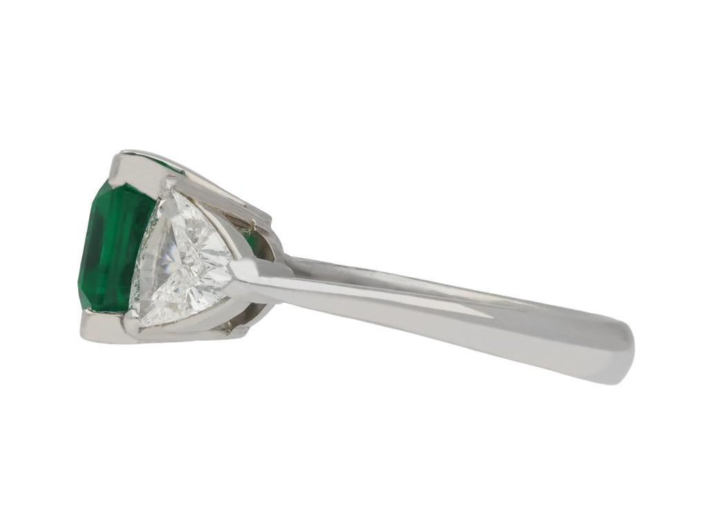 Colombian emerald and diamond flanked solitaire ring. Centrally set with an octagonal step cut natural Colombian emerald with no colour enhancement and minor clarity enhancement, in an open back claw setting with a weight of 4.30 carats, flanked by