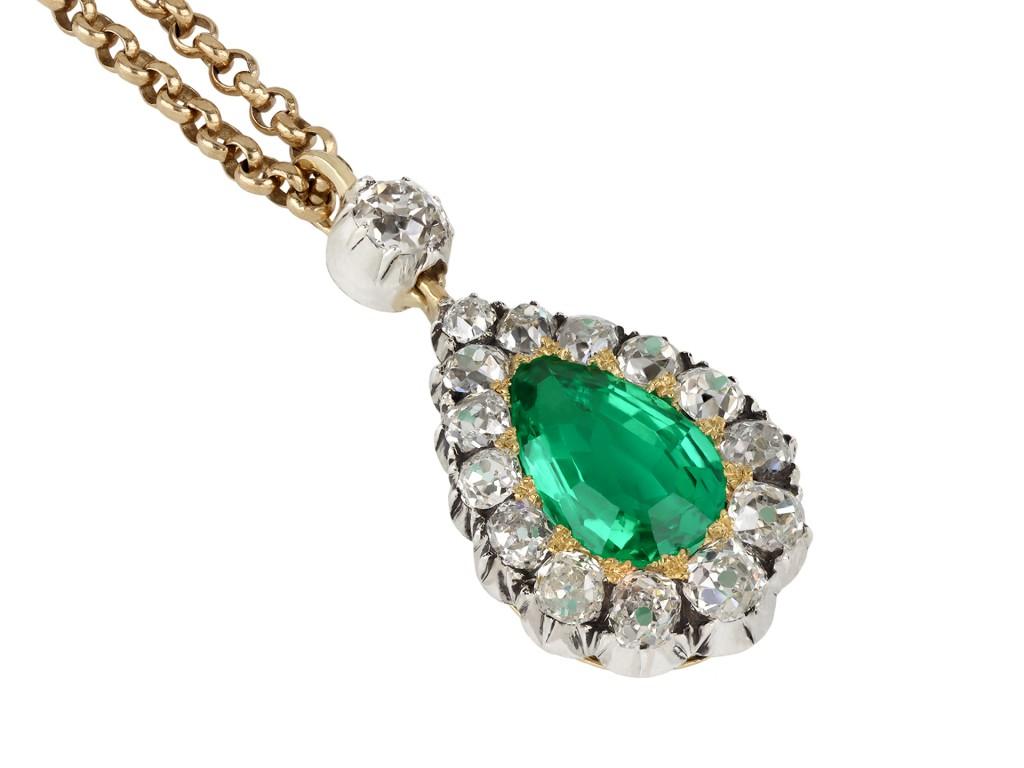 Colombian emerald and diamond pendant. Set to centre with a drop shape old cut natural Colombian emerald with no oil in an open back grain setting with an approximate weight of 1.88 carats, encircled by fourteen cushion shape old mine diamonds in