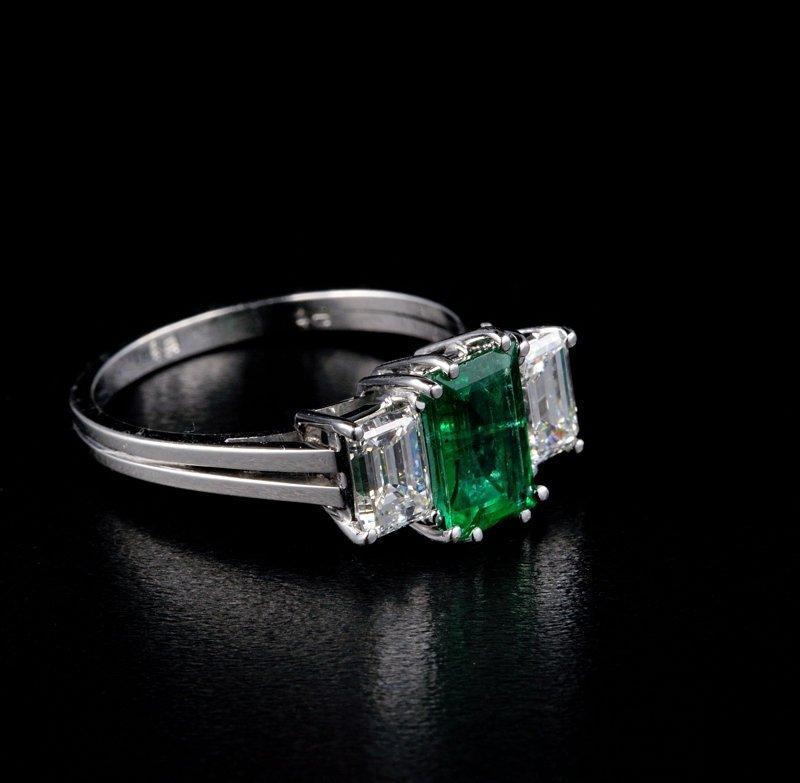 An elegant Art Deco trilogy Colombian emerald and diamond engagement ring.  The emerald cut emerald has a slightly bluish-green hue and it is 1.50 carat, certified by the world renowned CDTEC gemmological laboratory in Bogota, Colombia.  The side