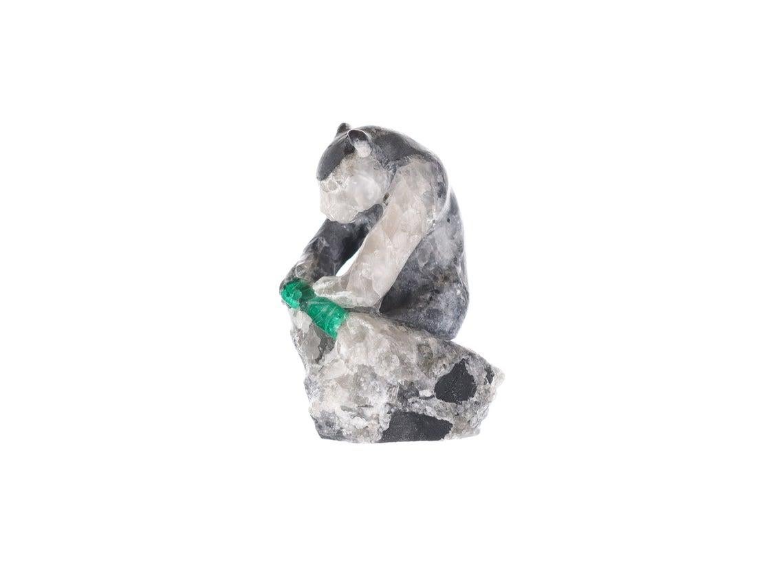 This beautiful and one-of-a-kind rough Colombian emerald sculpture features a hand-carved Bear made of gray shale and calcite. It is holding a piece of rock containing rough Colombian emeralds and white calcite below its feet. The detail of this