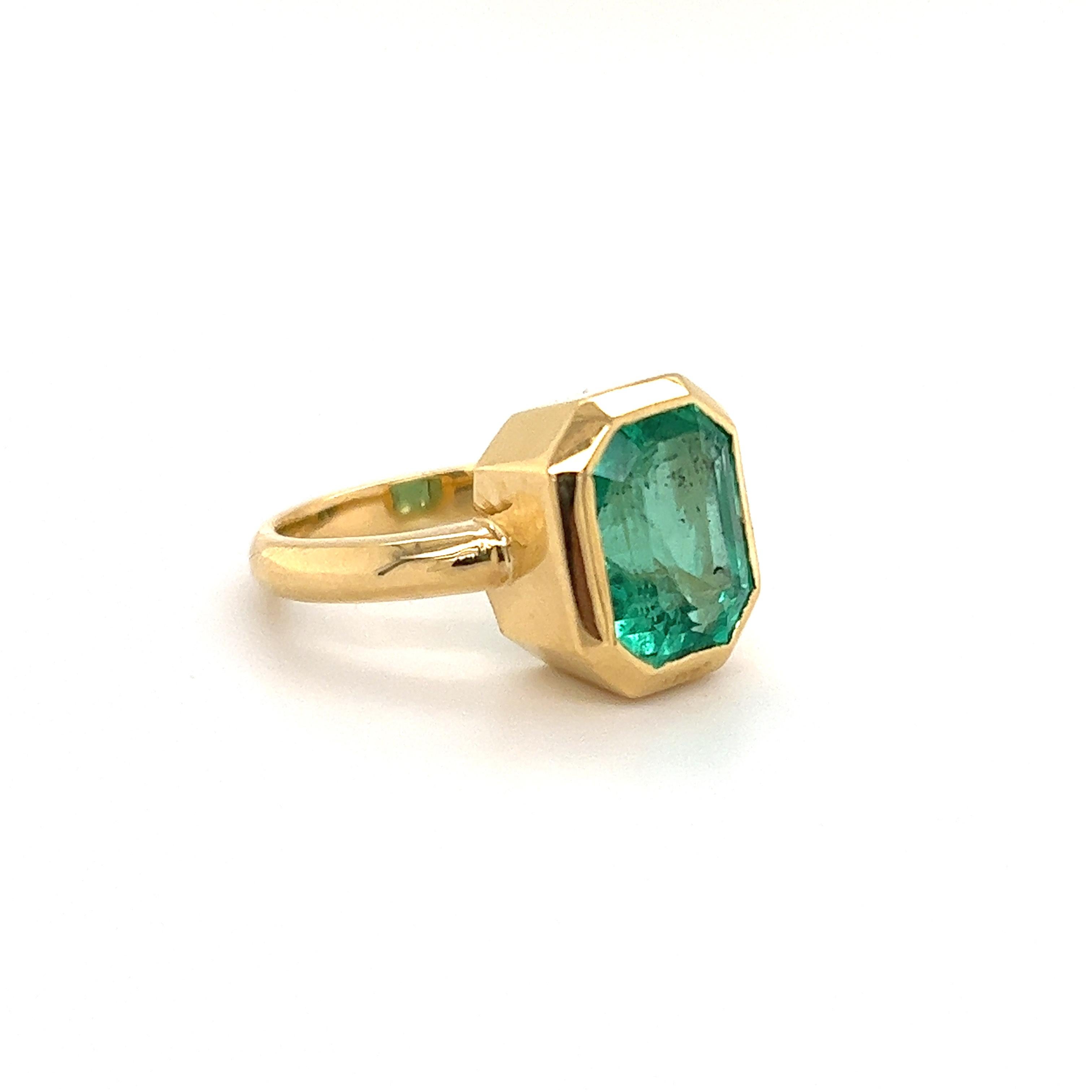 Beautiful ring crafted in 18k yellow gold. The ring highlights one Colombian Emerald gemstone with a vibrant green color. The emerald gemstone is bezel set in the ring showing sharp definition and nestled perfectly into the yellow gold design. The