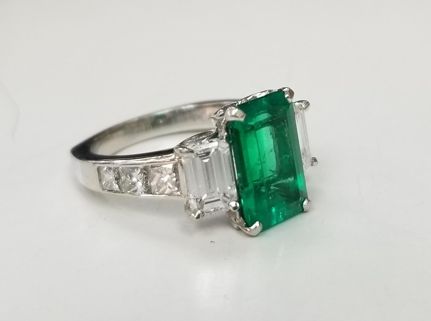 This is a vintage Platinum GIA Certified Colombian emerald and diamond ring. The center stone is 2.92 carat weight with a fine medium color and good clarity. There are 2 emerald cut diamonds weighing 1.46 carat total weight . and 6 princess cut and