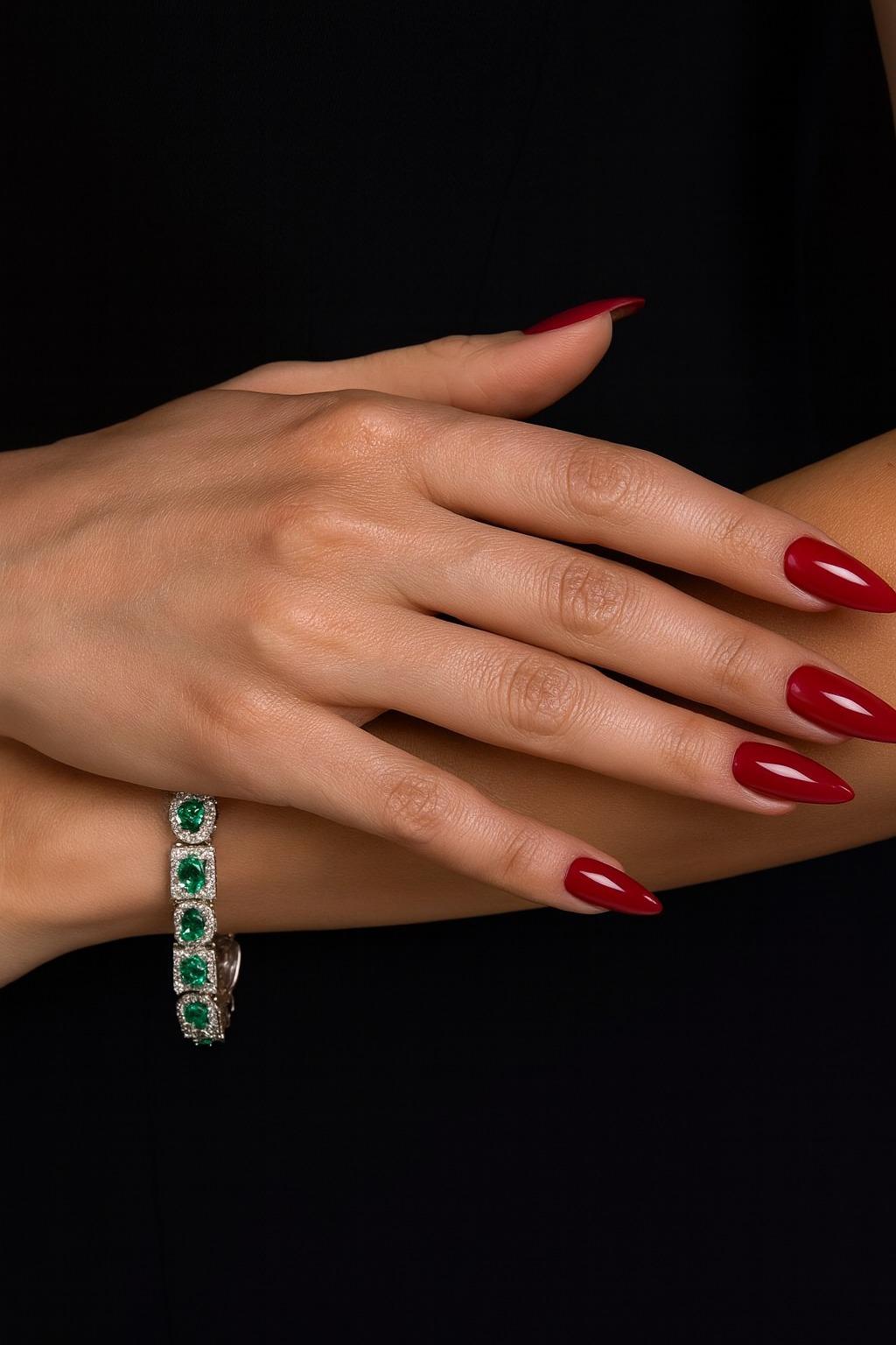 This highly important Colombian emerald and diamond tennis bracelet features a captivating arrangement of 6.00 carats of vivid green emeralds, each framed by a halo of sparkling diamonds. Surrounding the emeralds are 240 round brilliant cut diamonds