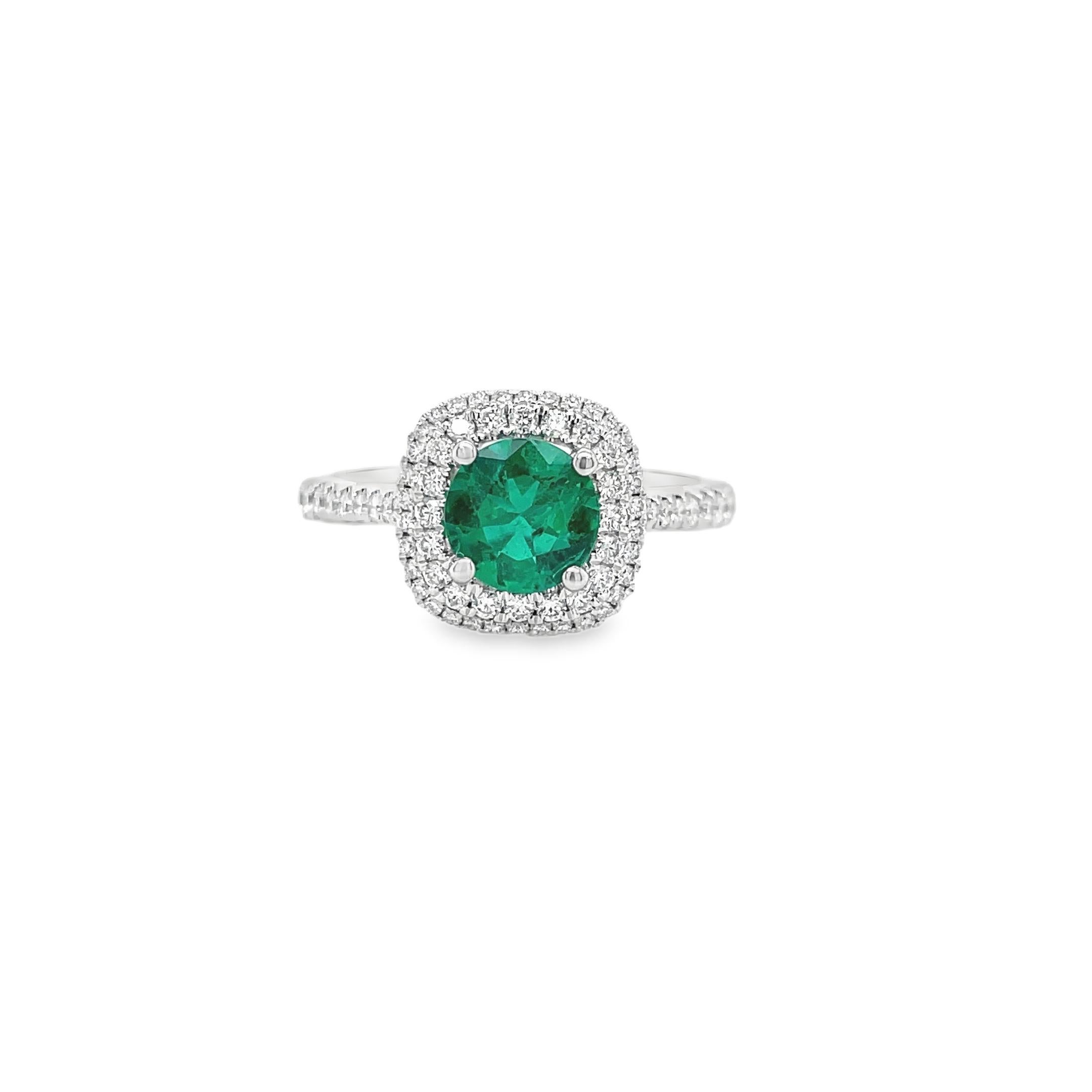 Ring contains one center round shape emerald weighing 0.65cts. Center stone is surrounded by a double row of round brilliant diamonds, 0.40tcw. Emearld and diamonds are mounted in handmade prong settings. Diamonds are F in color and VS2 in clarity.