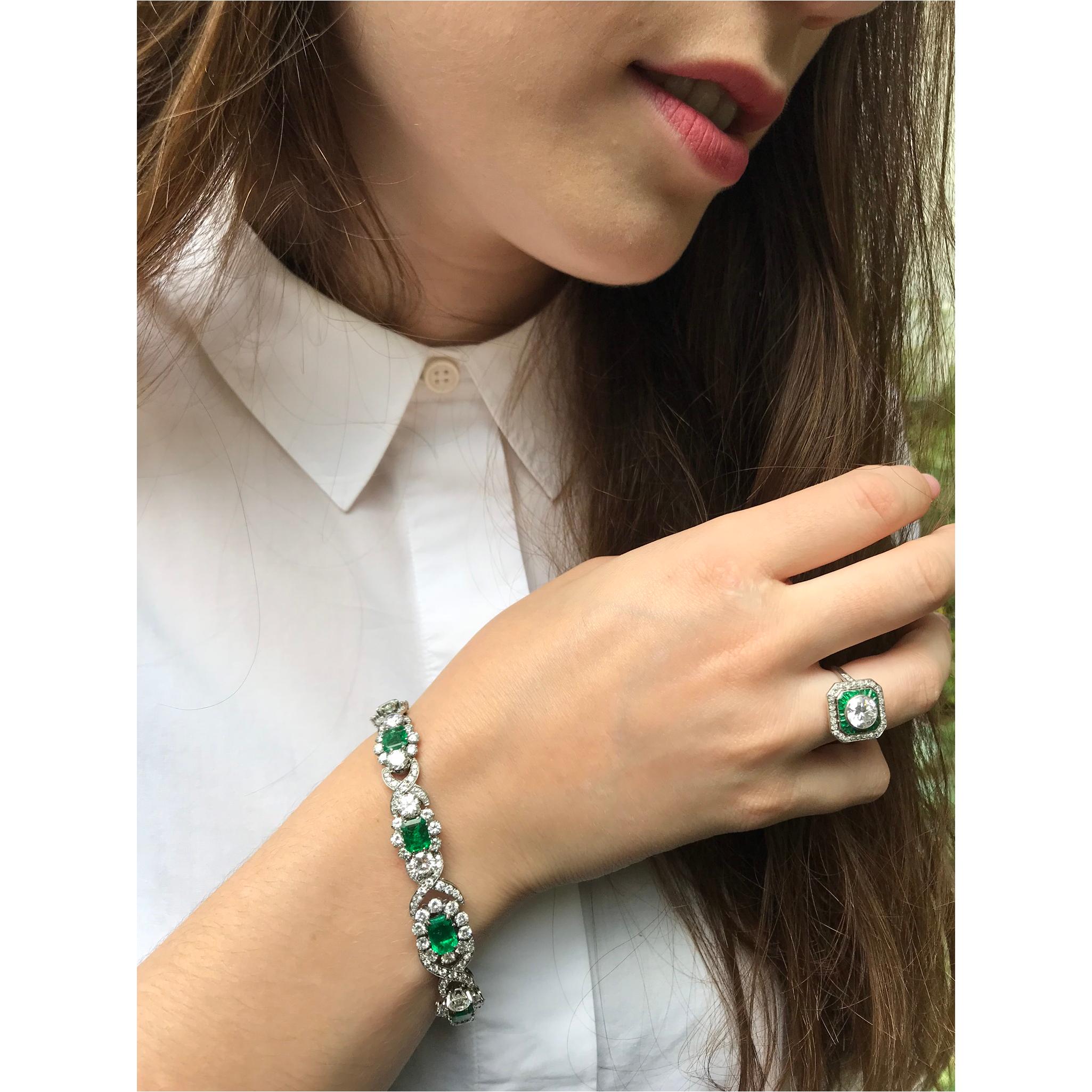 Through this magnificent 14K white gold Estate bracelet from 1950, a braid of 145 brilliant cut diamonds twists between nine degrading clusters of high quality brilliants and natural Colombian emeralds with a total weight of almost seven carats. On
