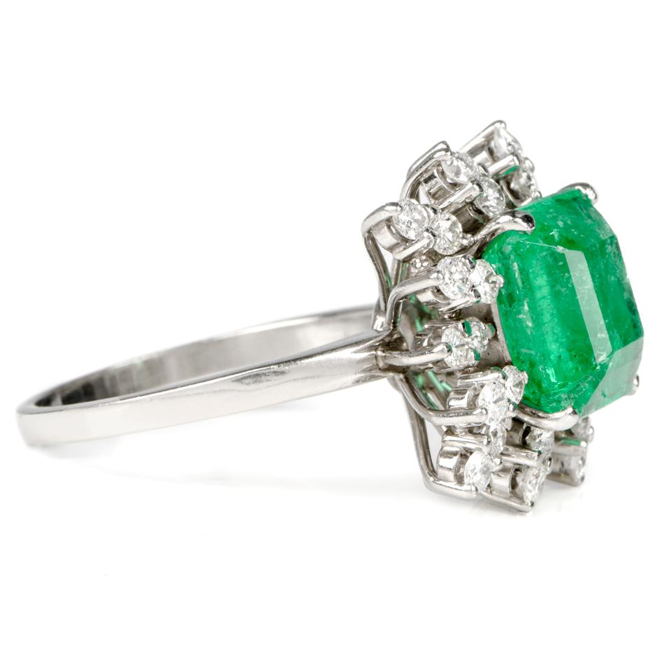 This beautiful emerald and diamond ring is crafted in solid 18-karat white gold, weighing 9.2 grams and measuring 17mm x 11mm high. Centered with one genuine Colombian emerald weighing approximately 4.10 carats, with a vibrant color. Surrounded by a