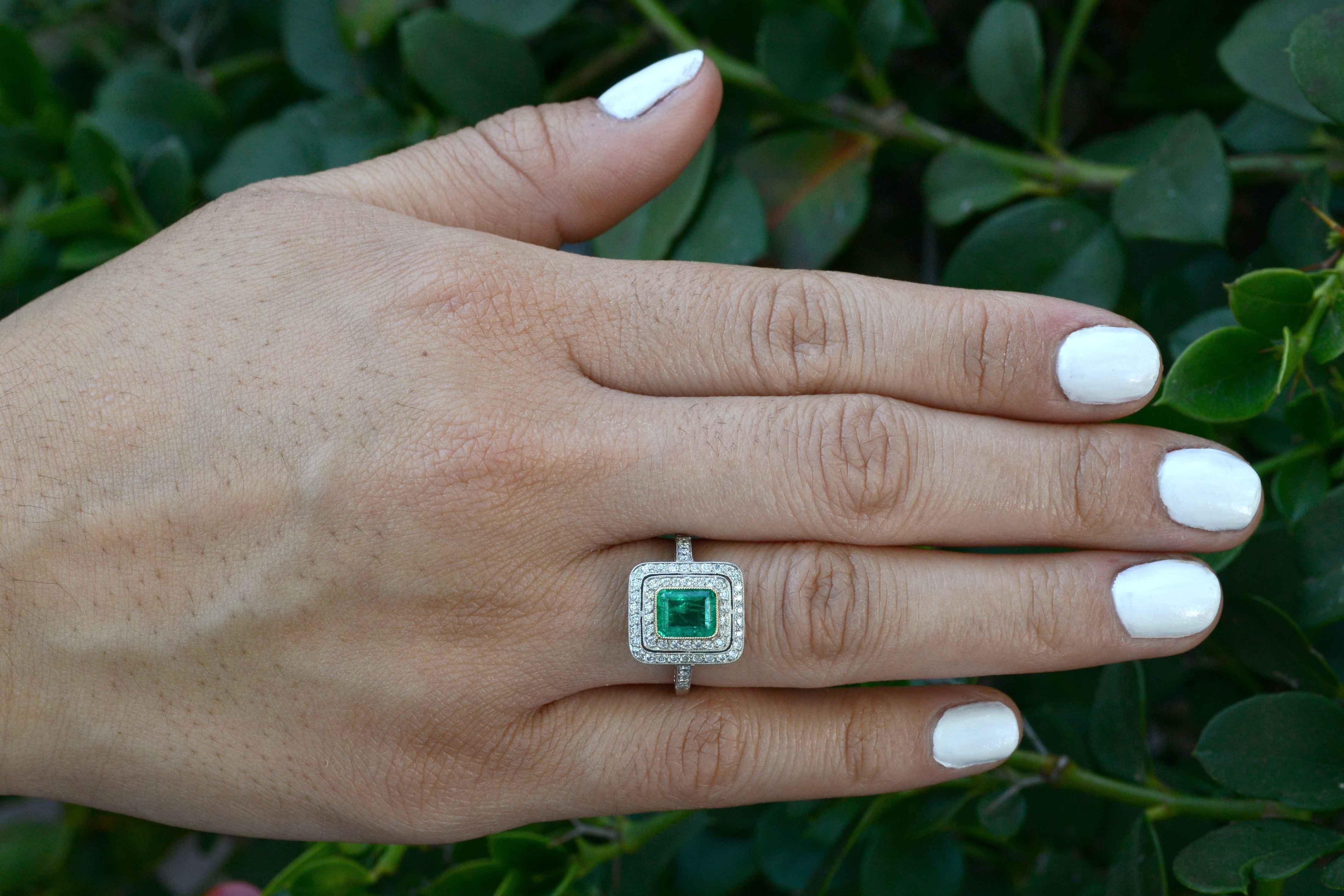 A dazzling Colombian Emerald takes center stage in this platinum engagement ring. The rich, vibrant , richly saturated green of the gemstone, set in a bezel of rich 18K yellow gold really POPS in the double pave' diamond halo. It seems to float in a