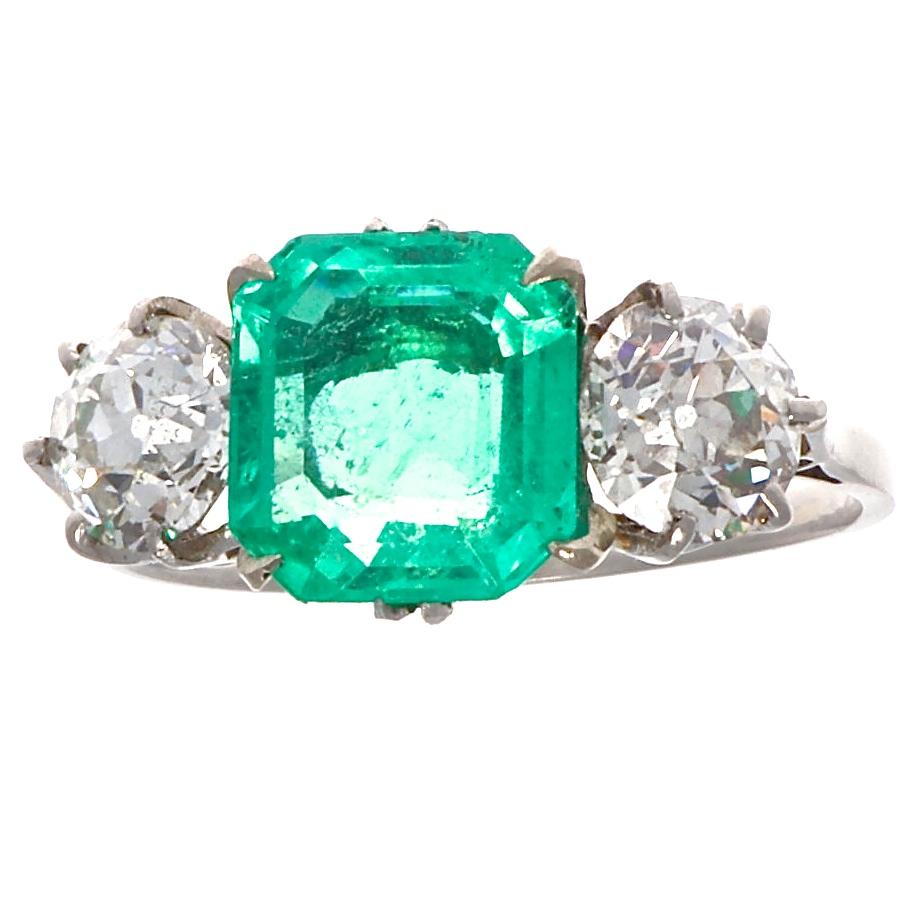 One lively 1.90 carat Colombian emerald is accompanied by two old European cut diamonds, approximately 0.60 carats each, G-H color and SI clarity. With scalloped sides and prongs in platinum, the design is delicate while the size of the stones and