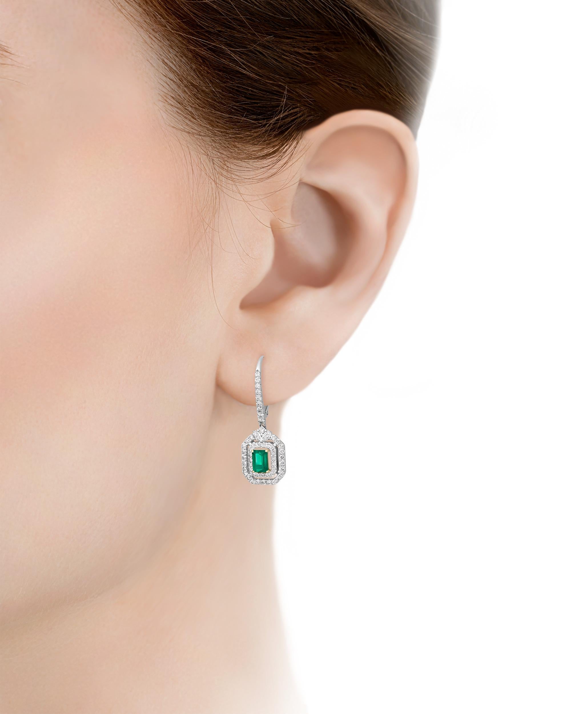 Two emerald-cut Colombian emeralds totaling 0.74 carats display the lush green hue for which stones from that region are so prized in these exceptional dangle earrings. Surrounding these jewels are shimmering white diamonds in a timeless geometric