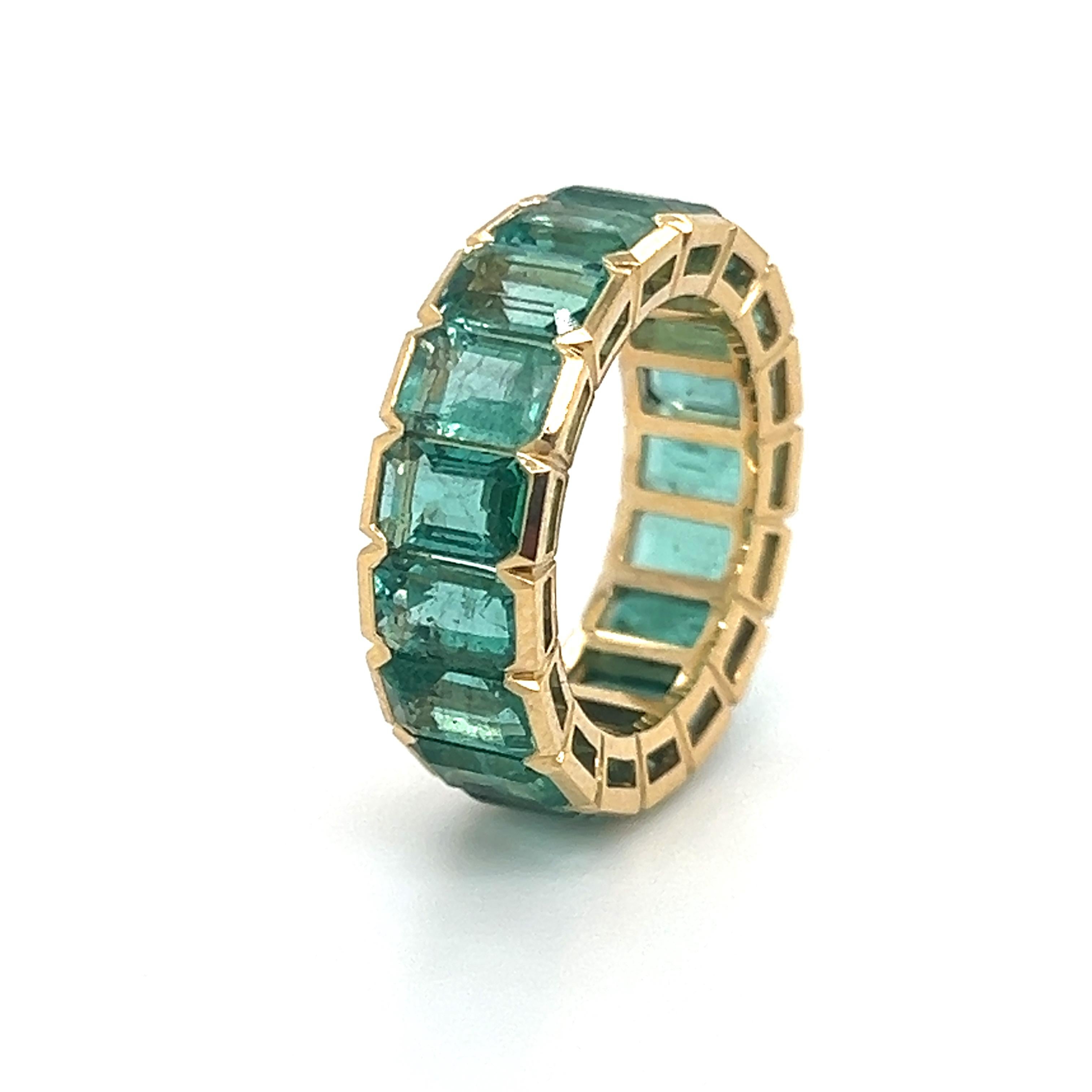 One of a kind hand crafted ring in 18k yellow gold. The highlights seventeen Colombian emerald gemstones that display a vibrant green color.  Each emerald in the ring weighs approximately 0.55 carat, giving the ring a 9.35 total carat weight. 
This