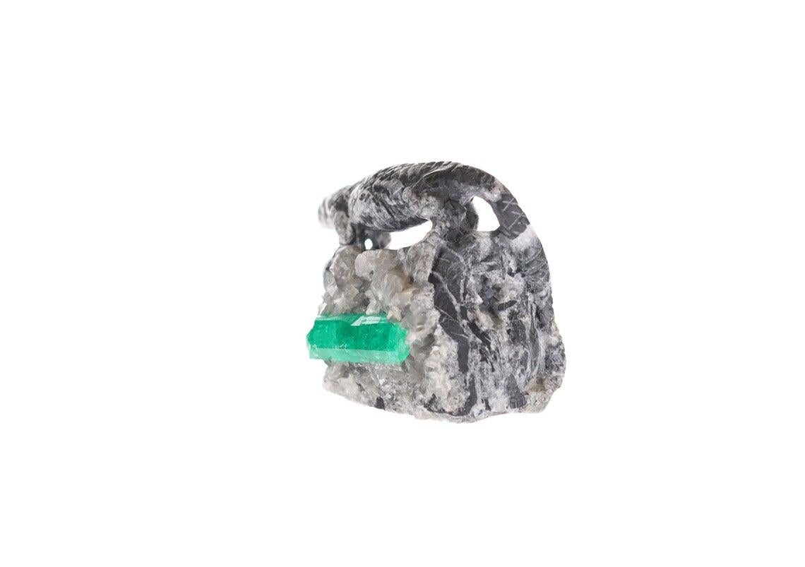 This is a beautiful and one-of-a-kind rough Colombian emerald sculpture. Featuring a rare and exotic, hand-carved Komodo Dragon made of black and gray shale, walking on top of large rock made of calcite with a very large Colombian emerald rough. The
