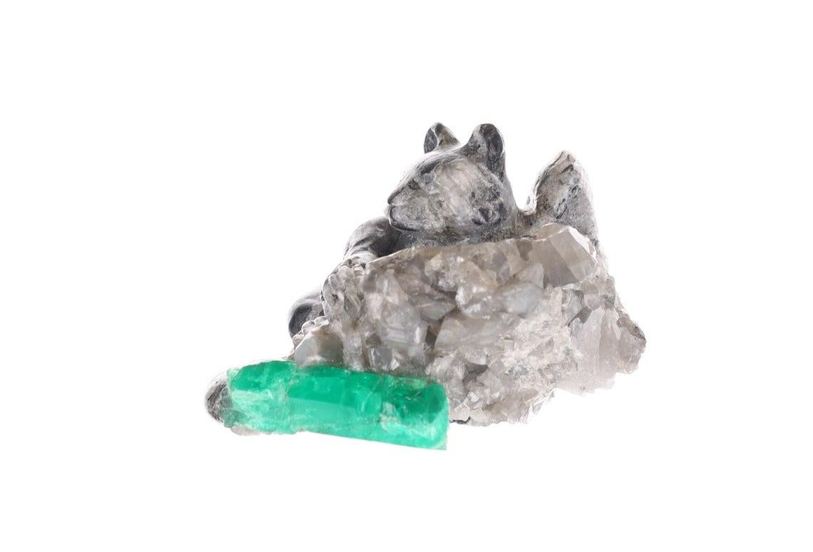 This beautiful and one-of-a-kind rough Colombian emerald sculpture. Featuring the one and only red panda; hand-carved with intricate detail along its coat and tail made of black and gray shale. The panda sits over a cliff with a natural Colombian