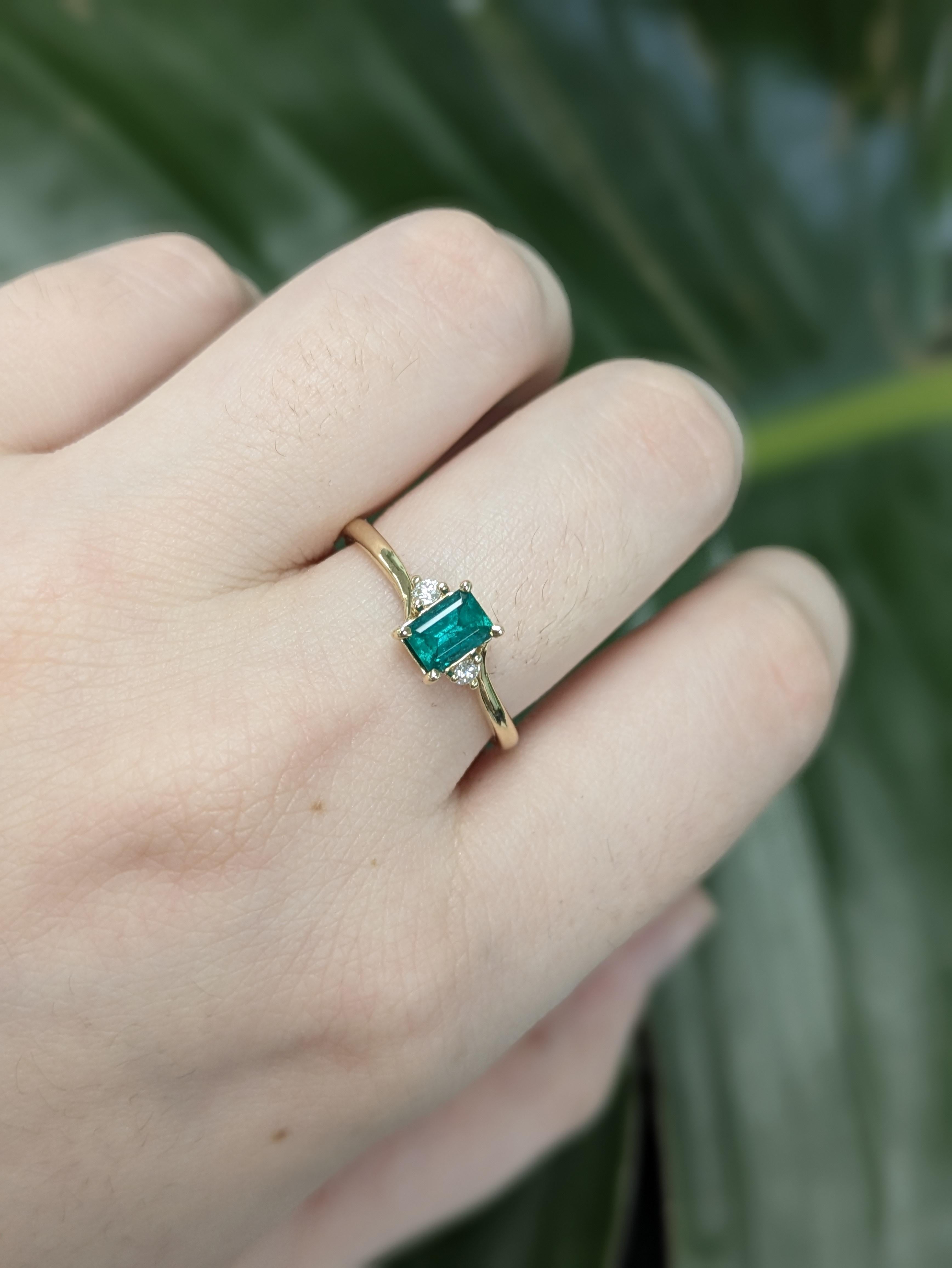 Cette élégante bague est ornée d'une émeraude colombienne de 0,38 carat de taille classique 6x4 mm, célèbre pour sa couleur verte vive et sa beauté naturelle. Sertie dans un anneau en or 14k pesant 1,88 gramme, l'émeraude est flanquée de deux