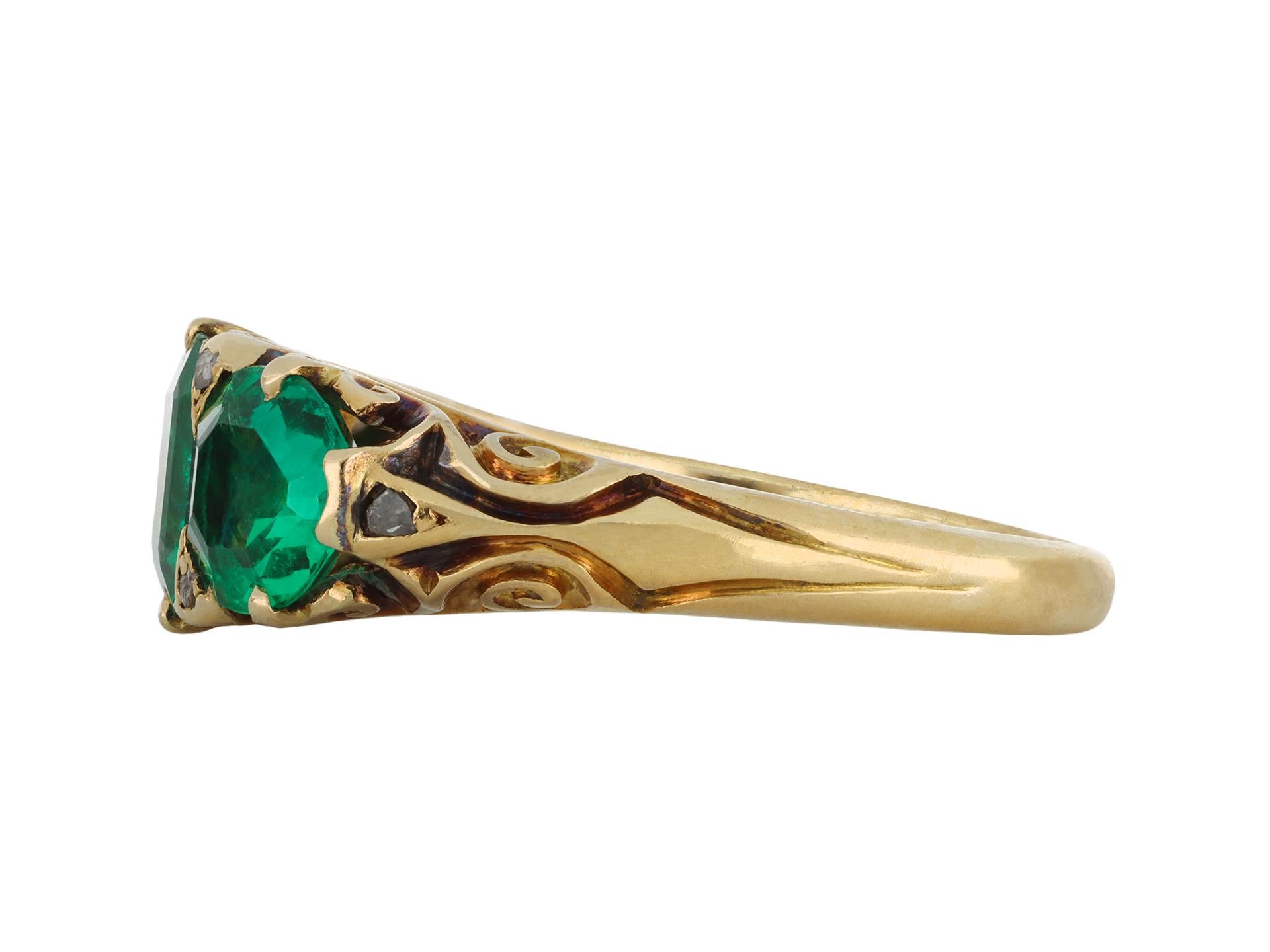 Colombian emerald three stone ring. Set with three octagonal mixed cut natural Colombian emeralds with minor clarity enhancement in open back claw settings with a combined approximate weight of 2.70 carats, further set with six round rose cut