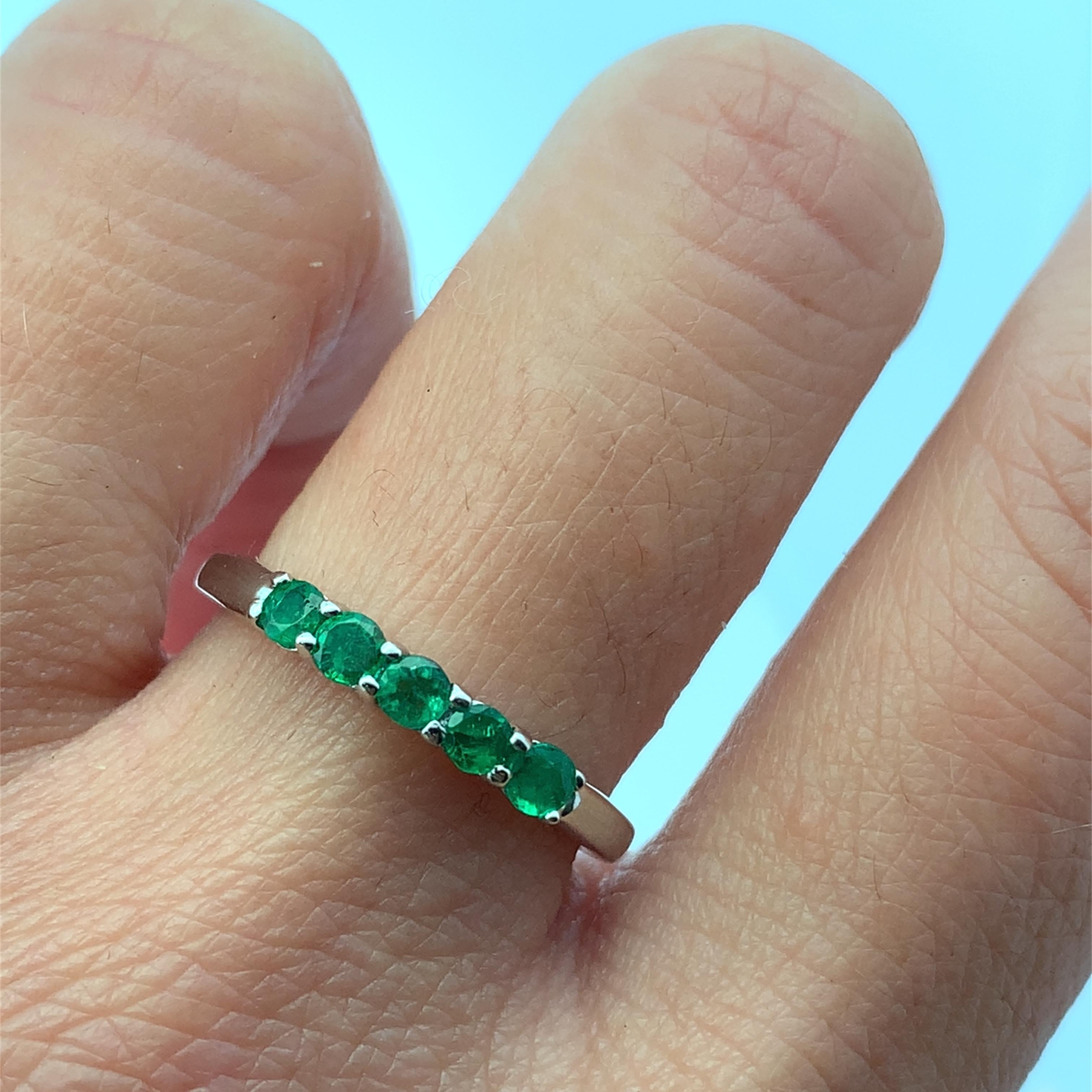 This stunning Colombian green emerald eternity band ring features five vibrant green emerald gemstones set in a sleek platinum band. Perfect for adding a touch of elegance to any outfit, this 0.56ct total weight Colombian emerald eternity ring is a