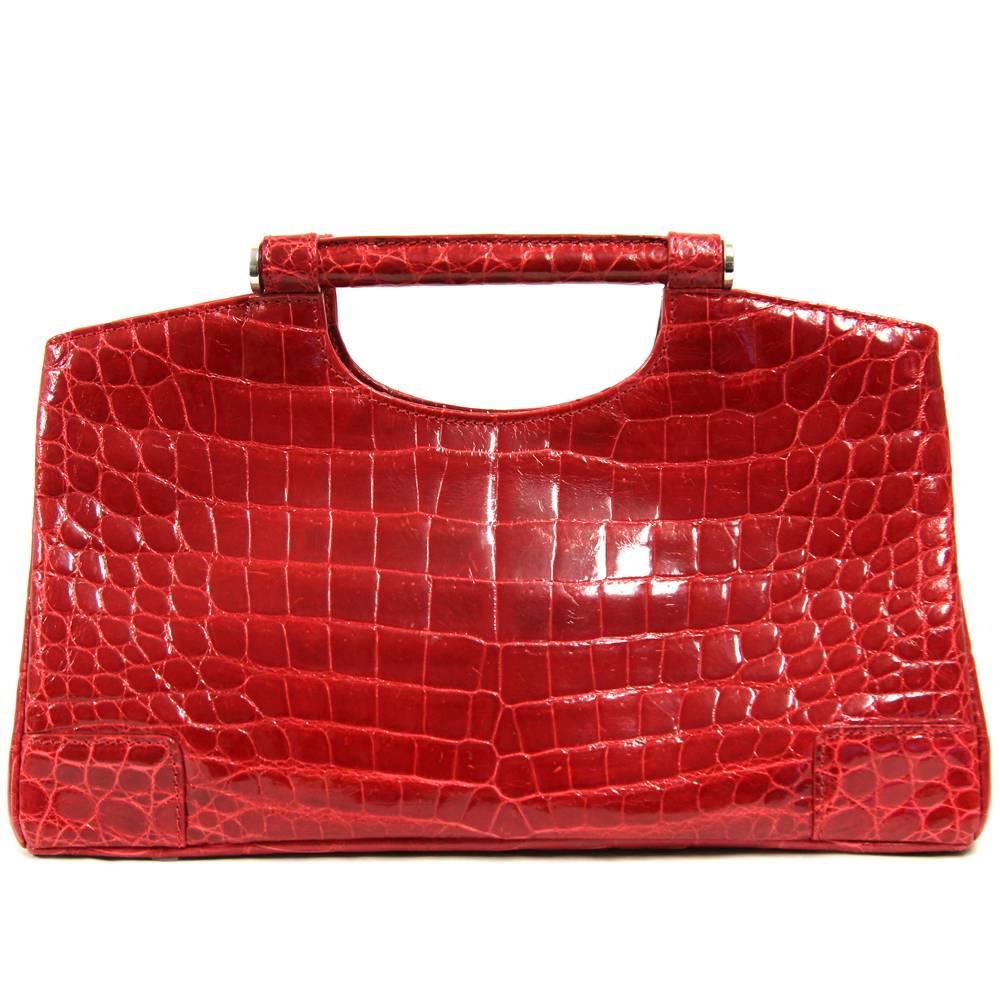 Pretty crocodile leather handbag in lively bordeaux color made by Colombo Via della Spiga with silver hardware. The bag features two coated iron handles, a press-button closure and two internal zipped pocket. Lined in suede. The item is vintage, it