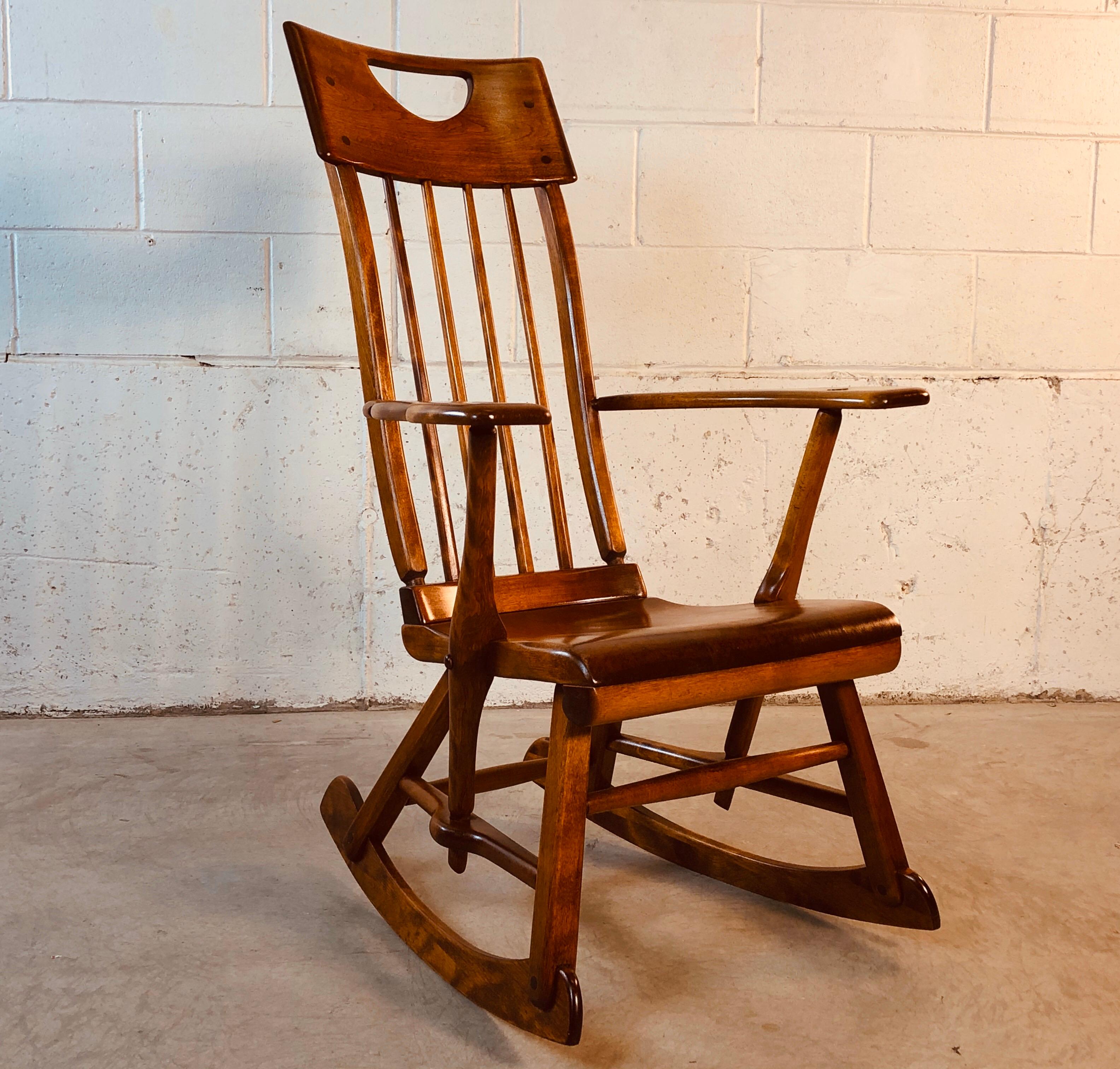 Colonial American style solid maple wood high-back rocking chair designed by Herman de Vries for Sikes Furniture Co. This rocking chair is from the 1930s and is all handmade. The chair has been restored and refinished and is in excellent condition.