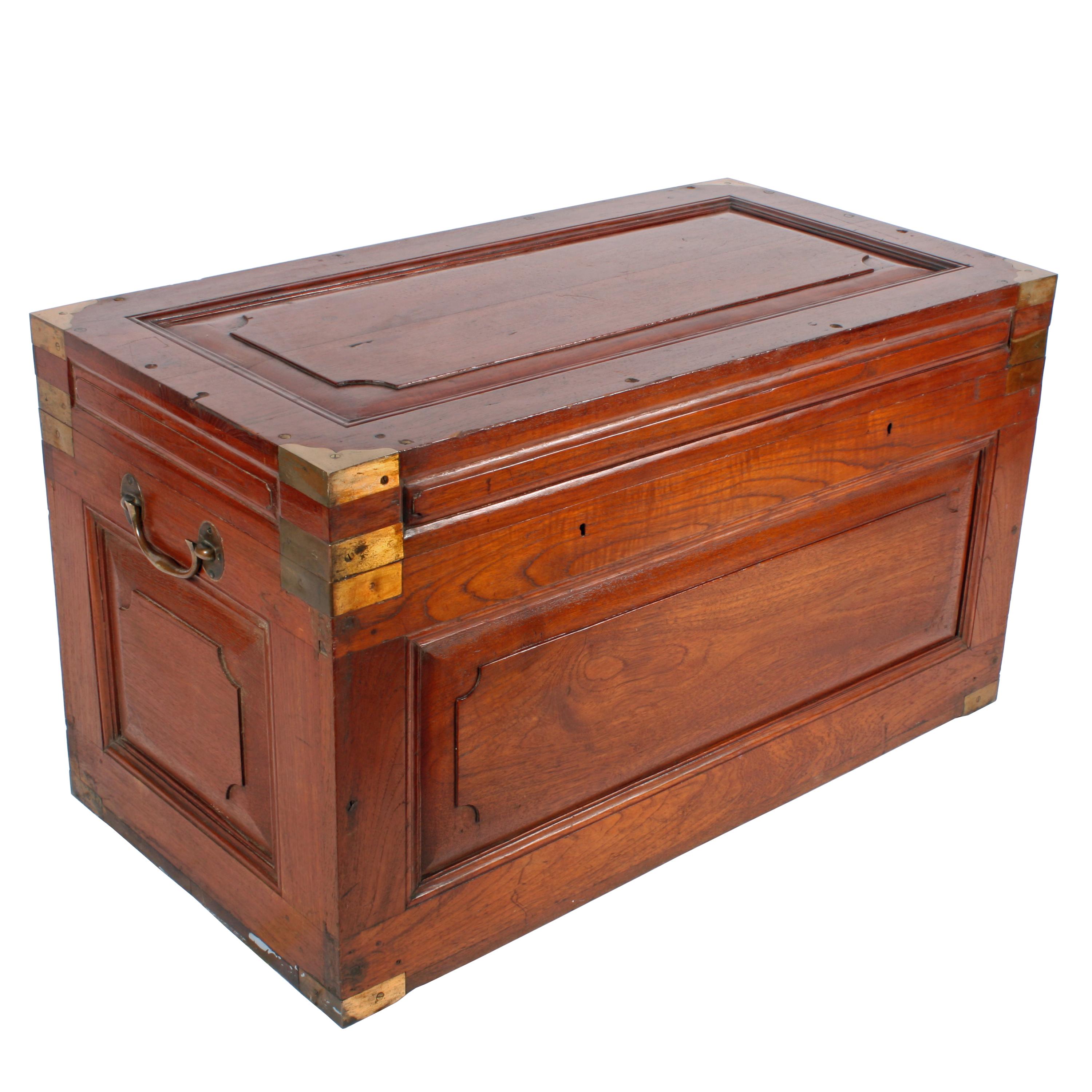 Colonial, brass-bound military teak trunk of unusual design, circa 1860. The top has an inset shaped, fielded panel and fluted moldings and there is a fielded panel decoration to the frieze. It is freestanding with conforming fielded panels on all