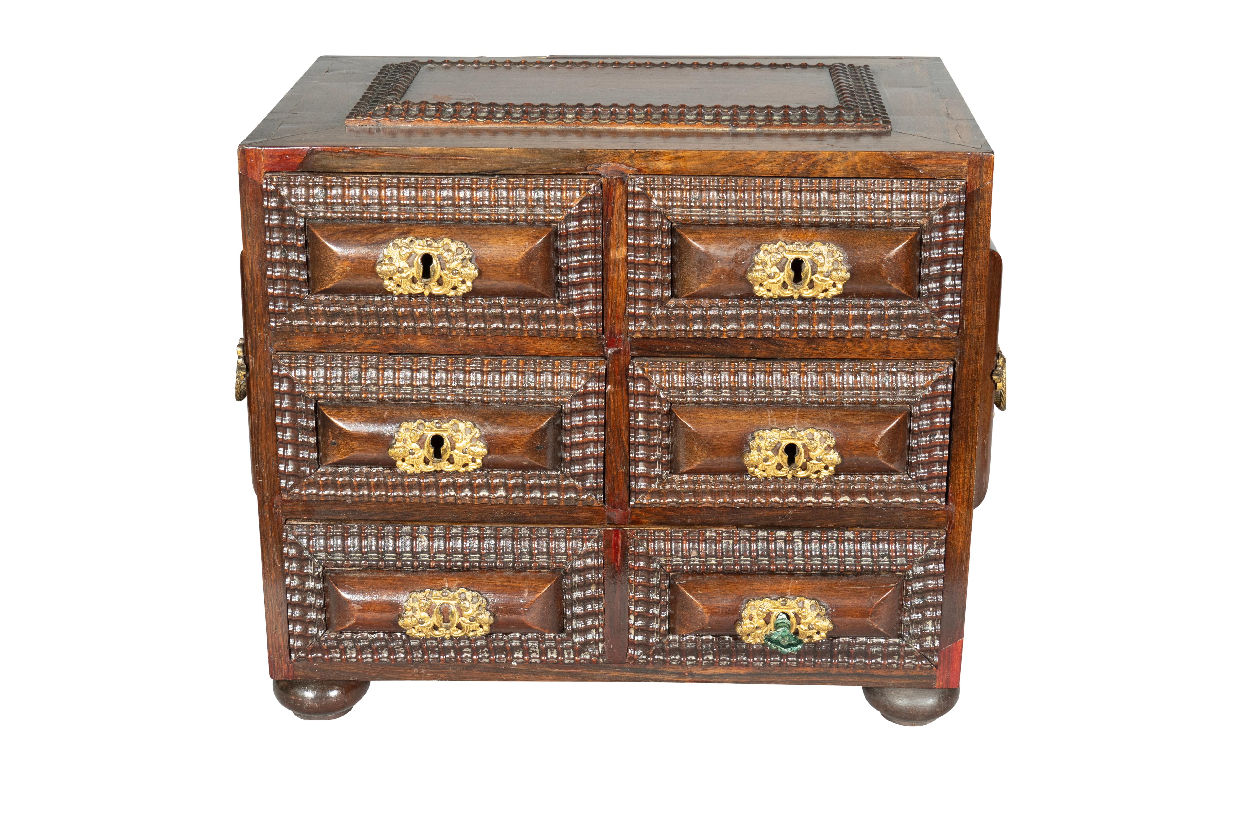 Arca enana colonial portuguesa utilizada para objetos de valor. Paneles elevados con herrajes de latón. Seis cajones pequeños. Pies de conejo.
