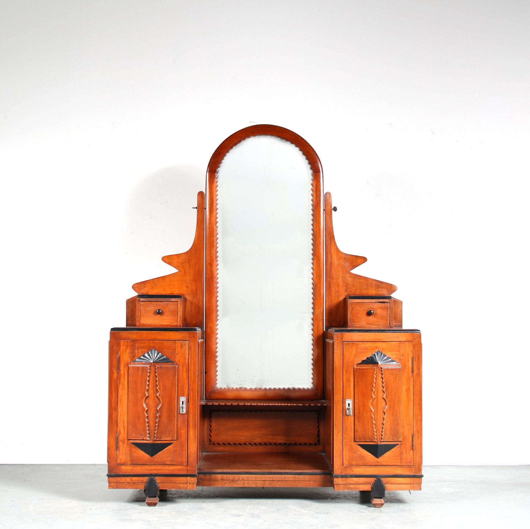 A colonial Amsterdam School dressing table, manufactured in the former Dutch East Indies, now Indonesia, around 1920.

This eye-catching piece is made of high quality wood in a nice warm brown colour. The centre of the piece holds a tall mirror in