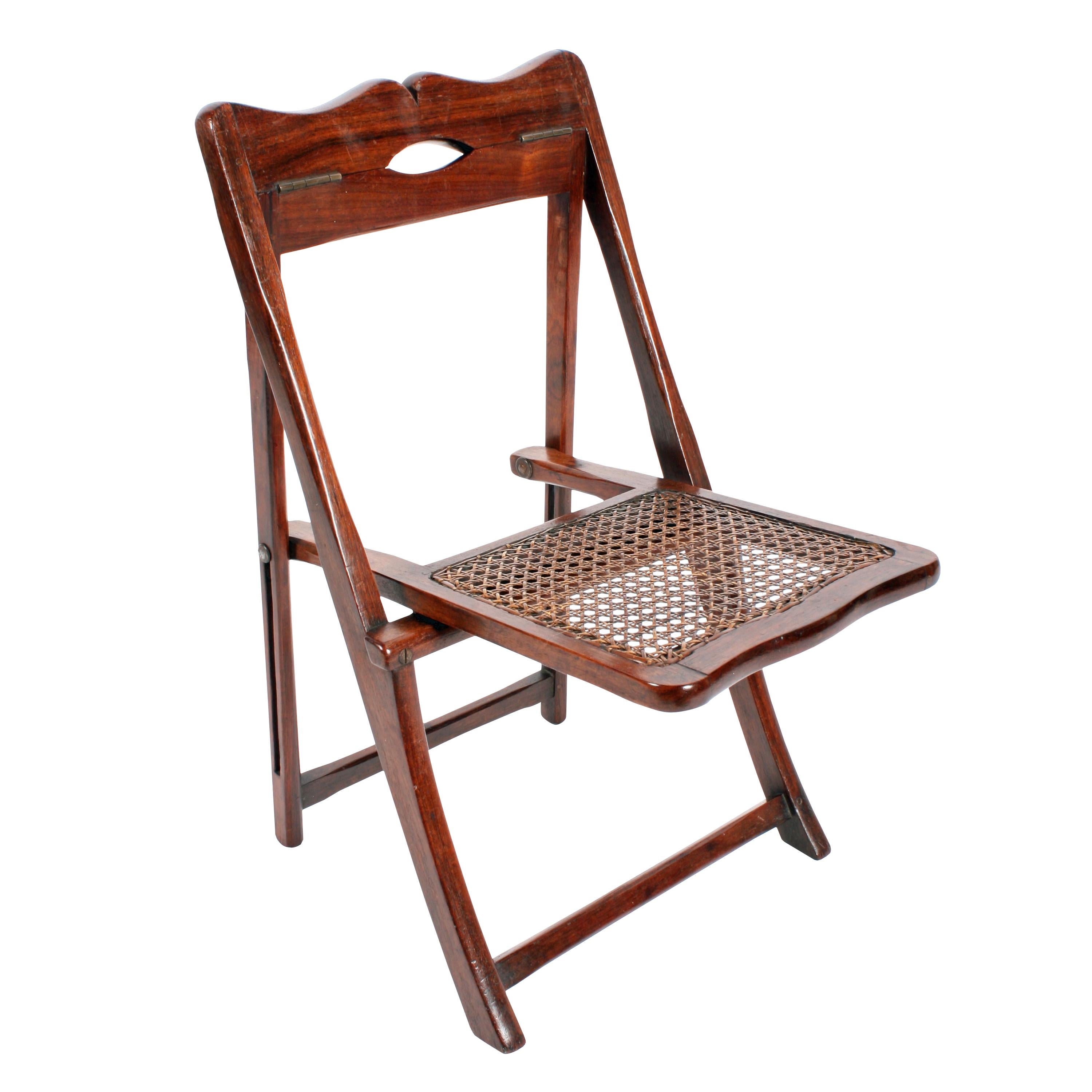 A late 19th-early 20th century colonial rosewood child's folding chair.

The chair has a bergère cane seat and brass hinges so it can fold completely flat.

The chair has a shaped top rail with a small hand hole in the centre.

The chair is in