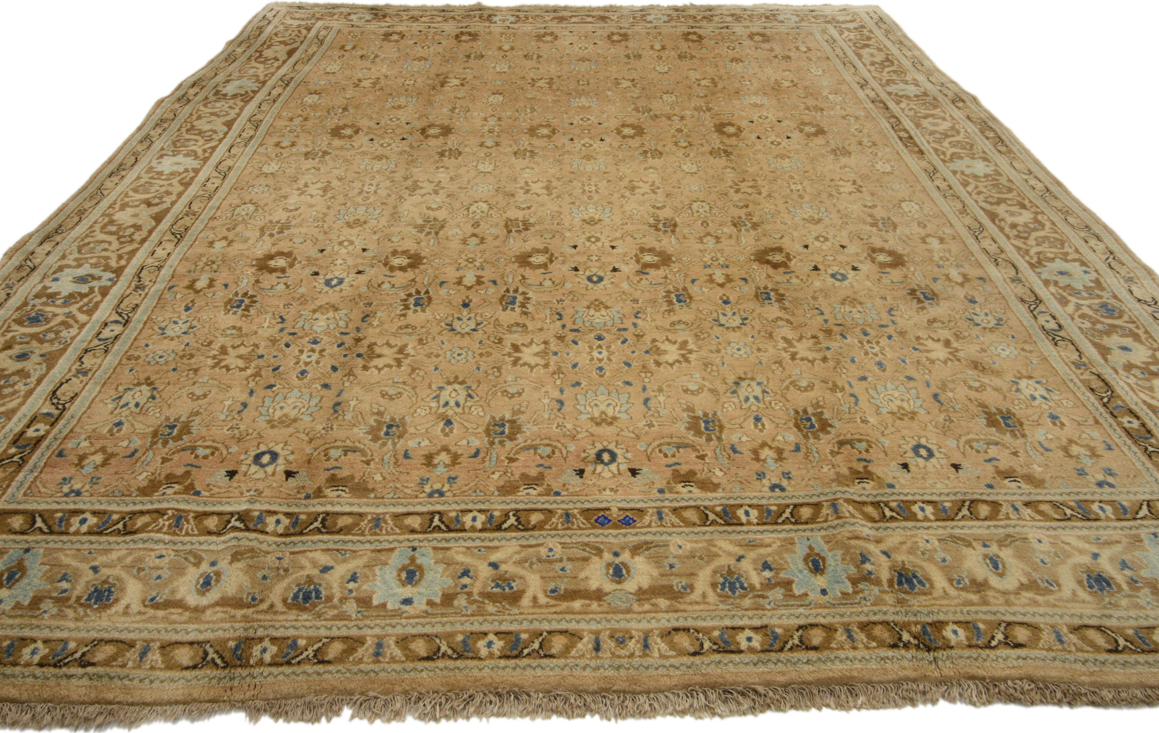 76144 Tapis persan vintage Mashhad de style néo-colonial aux couleurs chaudes et neutres. Ce tapis persan vintage Mashhad en laine nouée à la main présente un motif Shah Abbasi sur toute sa surface, réparti sur un champ abrasif. L'ancien motif