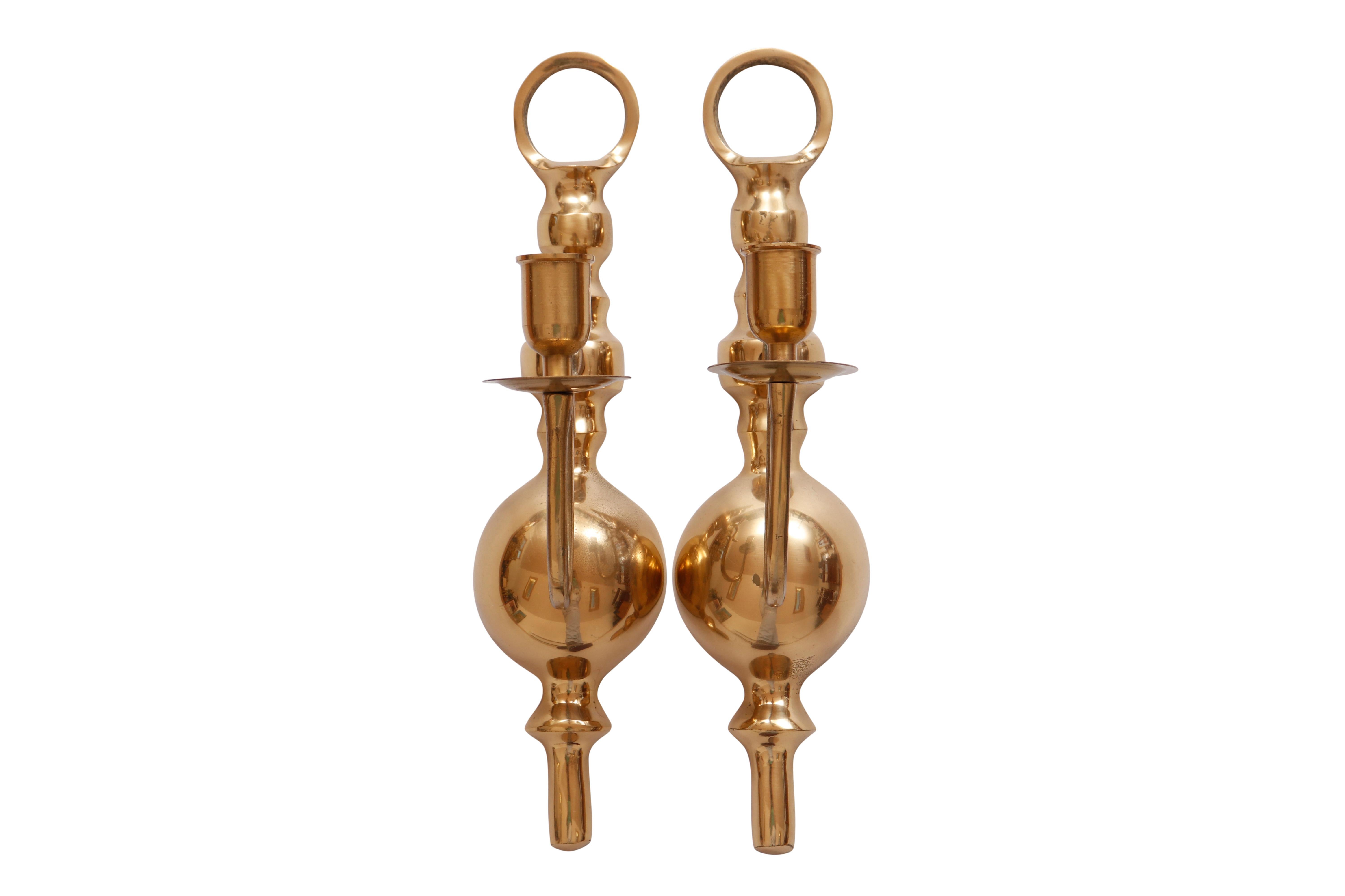 A pair of colonial style brass candle sconces. Decorative baluster shaped backplates support slender arms with scrolled backs. Finished with sleek capitals and bobeches. Dimensions per sconce.